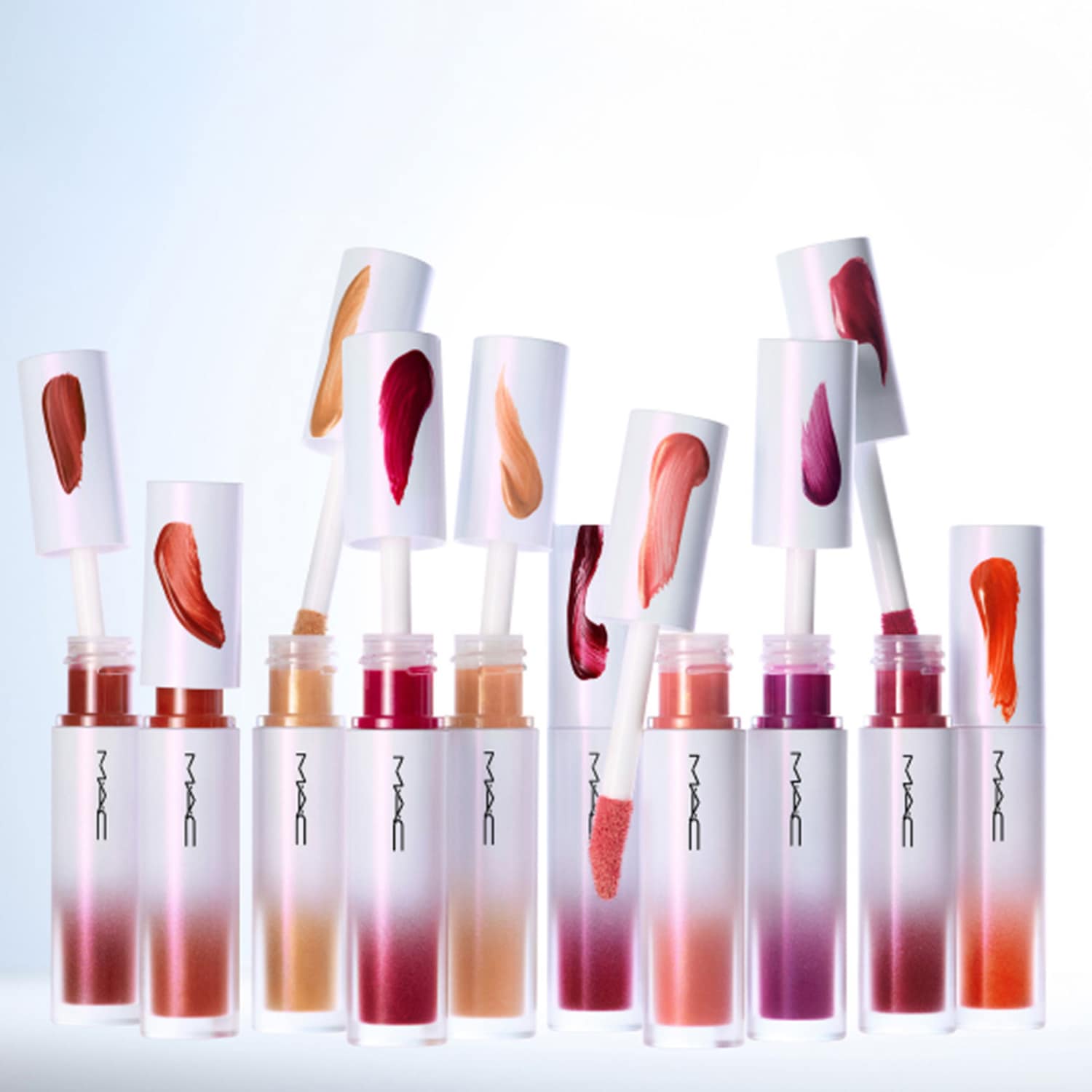 Ontdek de reeks MAC lipglosses in verschillende tinten, van zachte nude tot levendig rood, gepresenteerd in elegante, transparante verpakkingen met witte accenten.