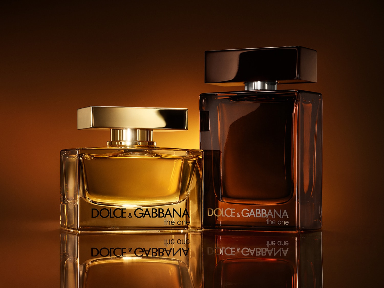 Due flaconi di profumo Dolce & Gabbana "The One", uno dorato e uno marrone scuro, emanano lusso ed eleganza.