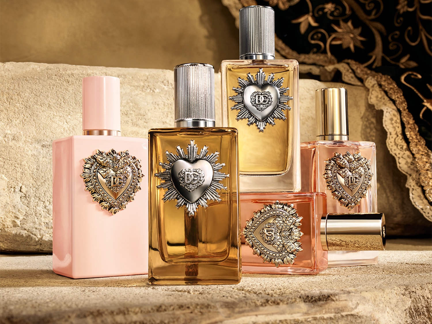 Esplora la collezione di profumi Dolce&Gabbana, ognuno con flaconi unici in tonalità oro, rosa e ambrate, adornati con il sacro cuore.