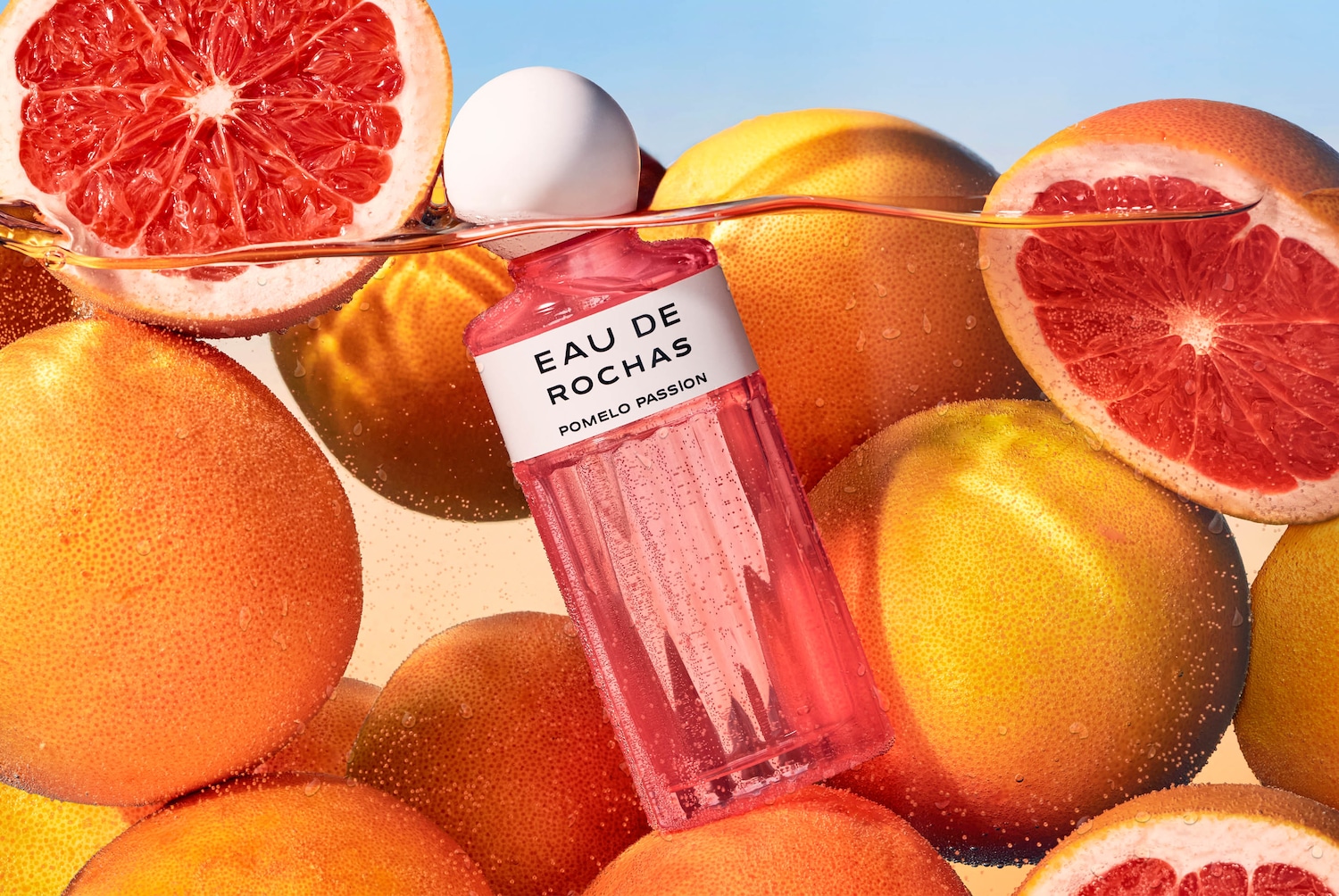 Découvrez Eau de Rochas Pomelo Passion, un parfum pétillant dans un flacon rose, entouré de pamplemousses juteux.