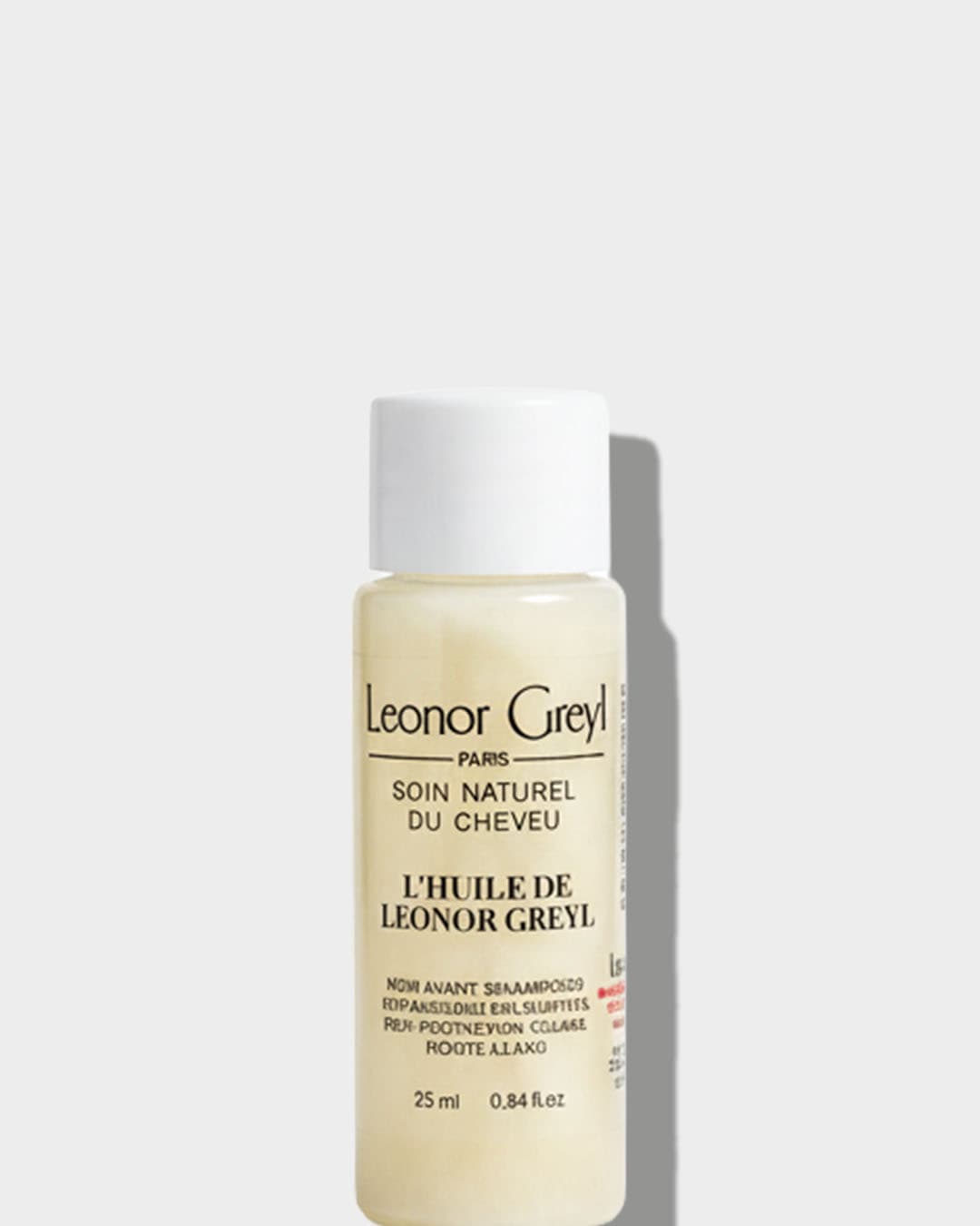 Butelka olejku do włosów Leonor Greyl o pojemności 25 ml z białą nakrętką, etykieta z czarnym napisem "Leonor Greyl Paris, Soin Naturel Du Cheveu, L'Huile de Leonor Greyl".
