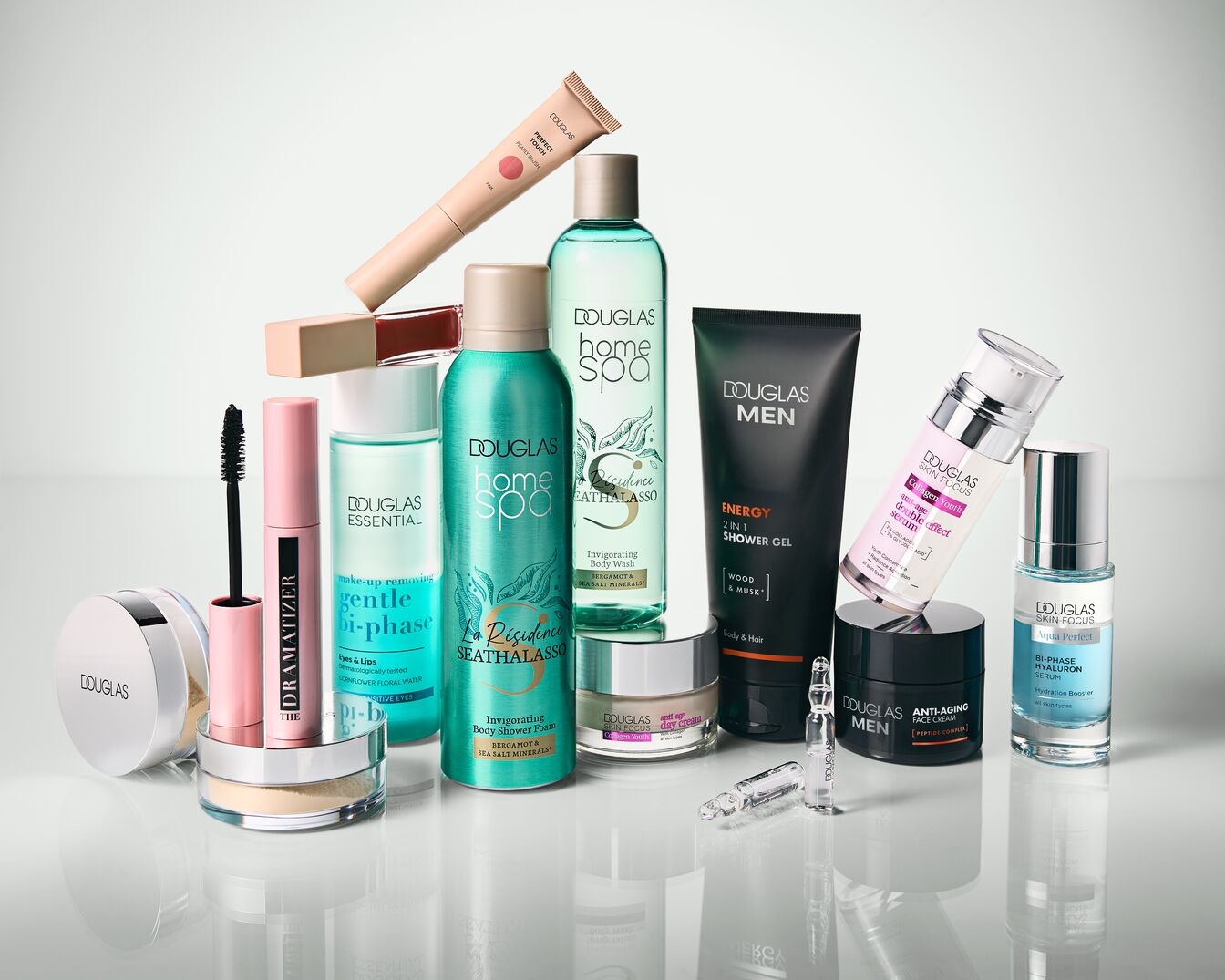 Różnorodność produktów Douglas, w tym kosmetyki do makijażu, pielęgnacji ciała i twarzy dla kobiet i mężczyzn, w eleganckich opakowaniach.