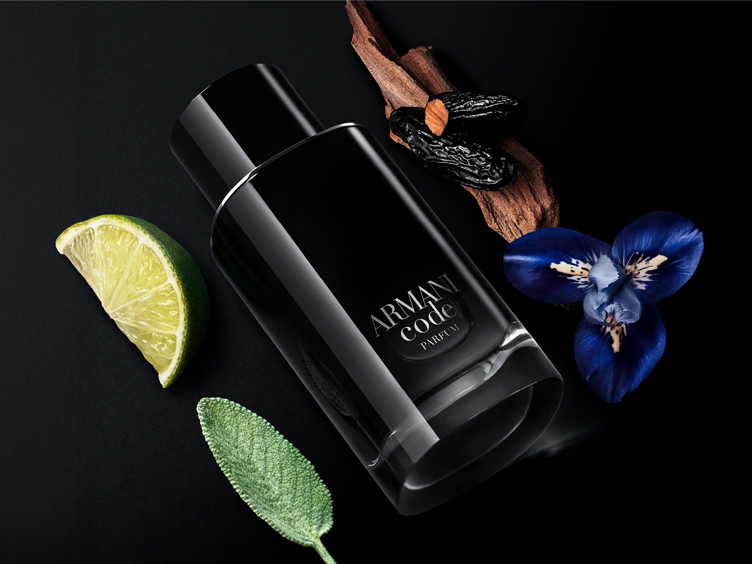 Een zwarte Armani Code parfumfles ligt tussen een schijfje limoen, een blauwe bloem en een takje.
