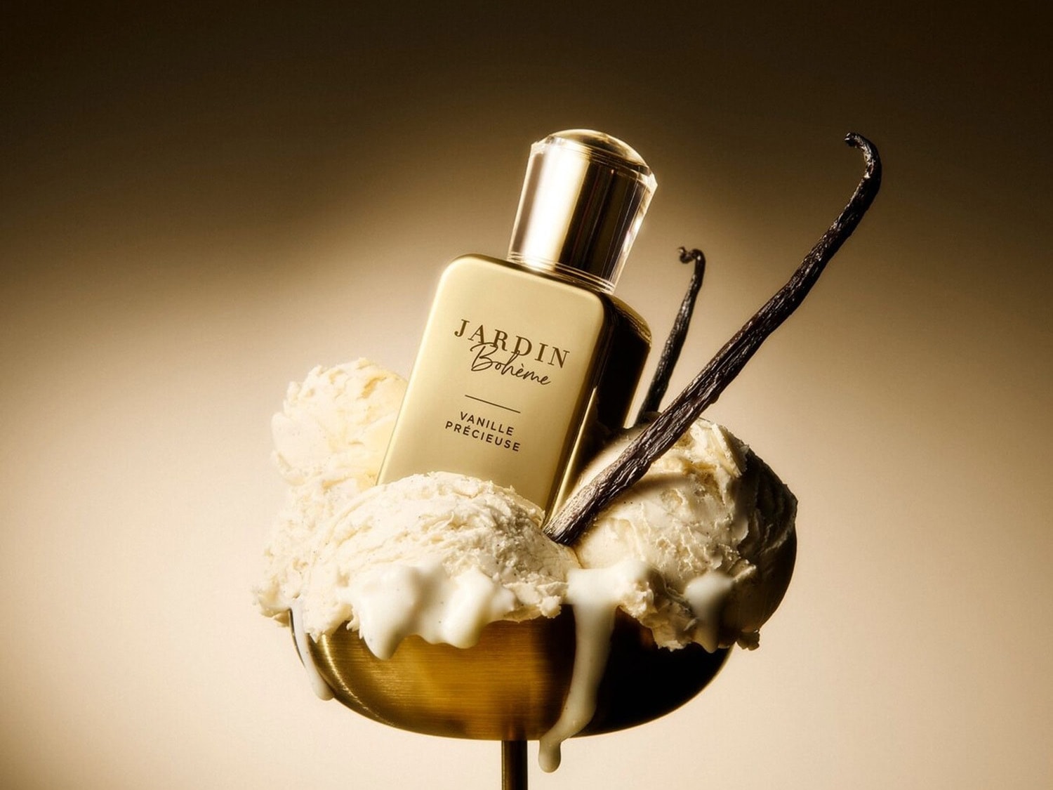 Gouden Jardin Bohème Vanille Précieuse parfumflesje, omringd door bolletjes vanille-ijs en vanillestokjes in een gouden kom.