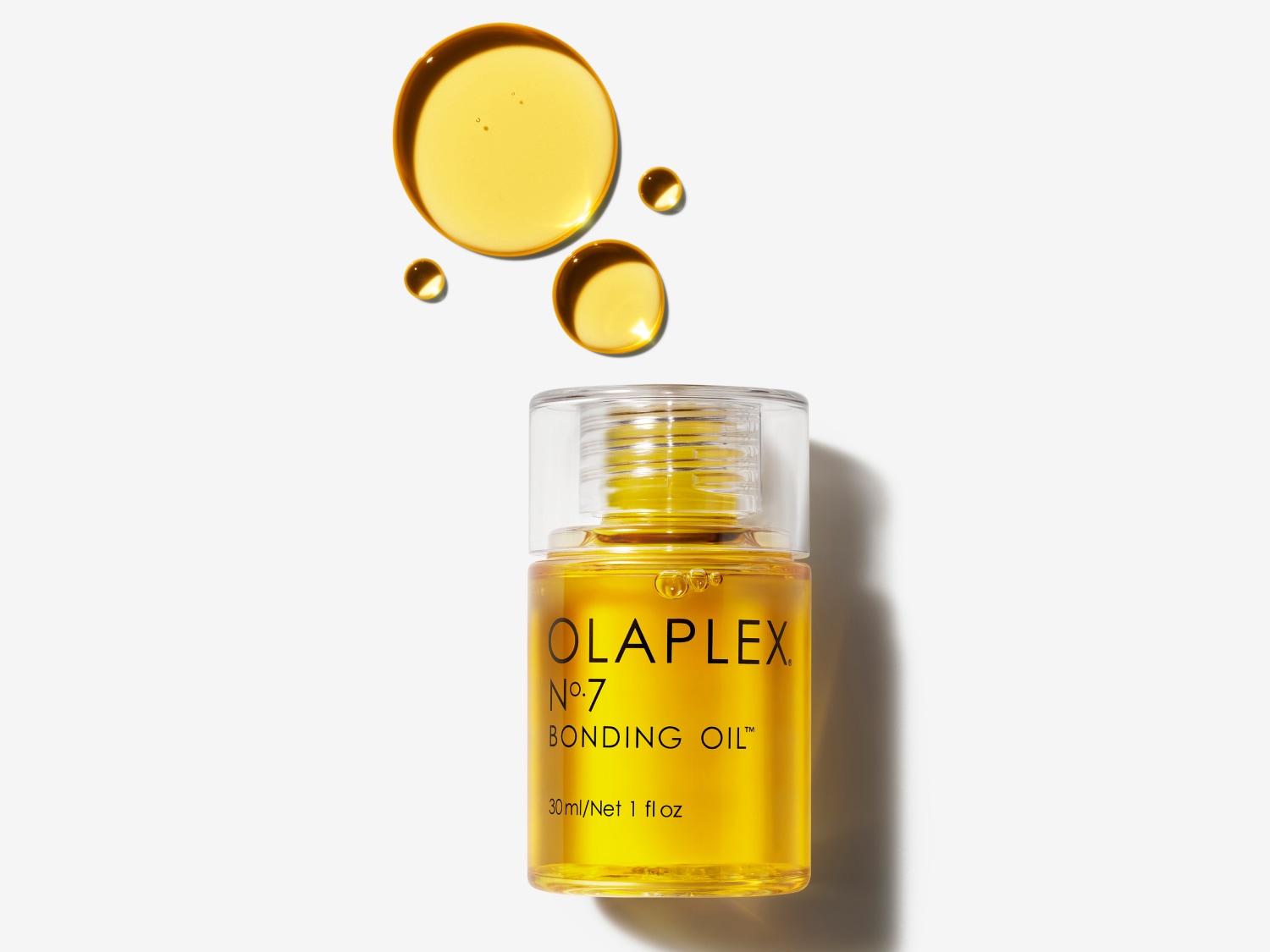 Olaplex No. 7 Bonding Oil in een heldere fles met een doorzichtige dop, omringd door gouden oliedruppels.