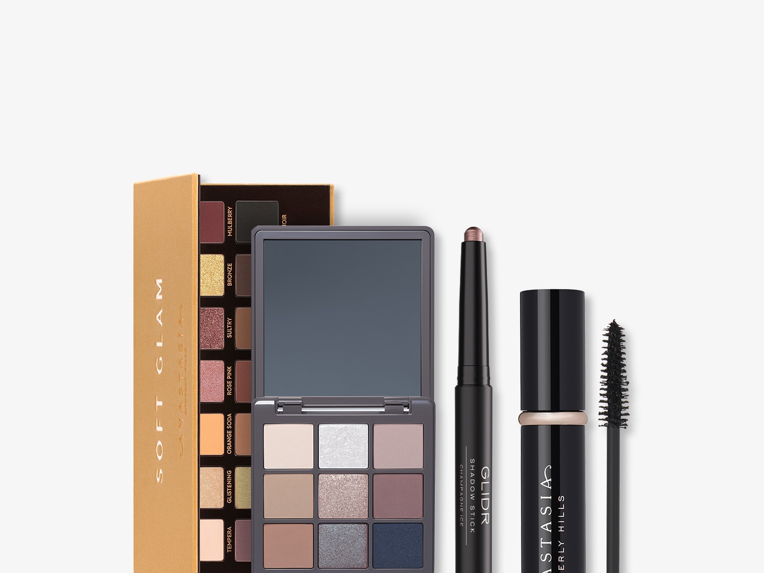 Paleta cieni do powiek Anastasia Beverly Hills Soft Glam w złotym opakowaniu, kompakt z lusterkiem, cień w sztyfcie Glidr Champagne Ice i tusz do rzęs Anastasia Beverly Hills.