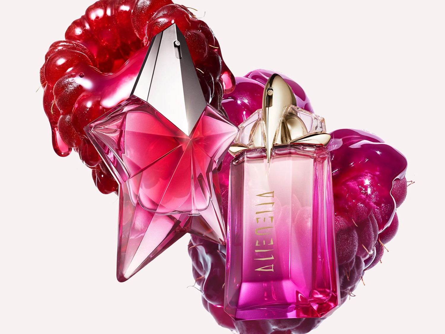 Deux flacons de parfum rose, l'un en forme d'étoile et l'autre rectangulaire, sont mis en valeur avec des framboises brillantes, évoquant un parfum fruité et luxueux.