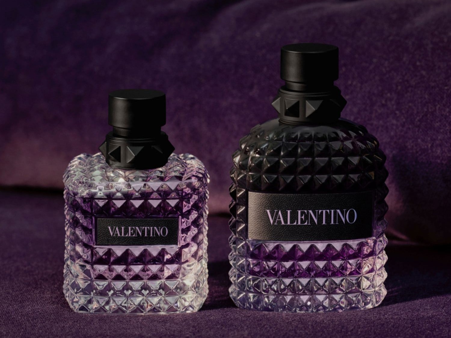Découvrez le parfum Valentino, présenté dans un flacon à motifs géométriques avec un bouchon noir clouté, sur un fond violet texturé.