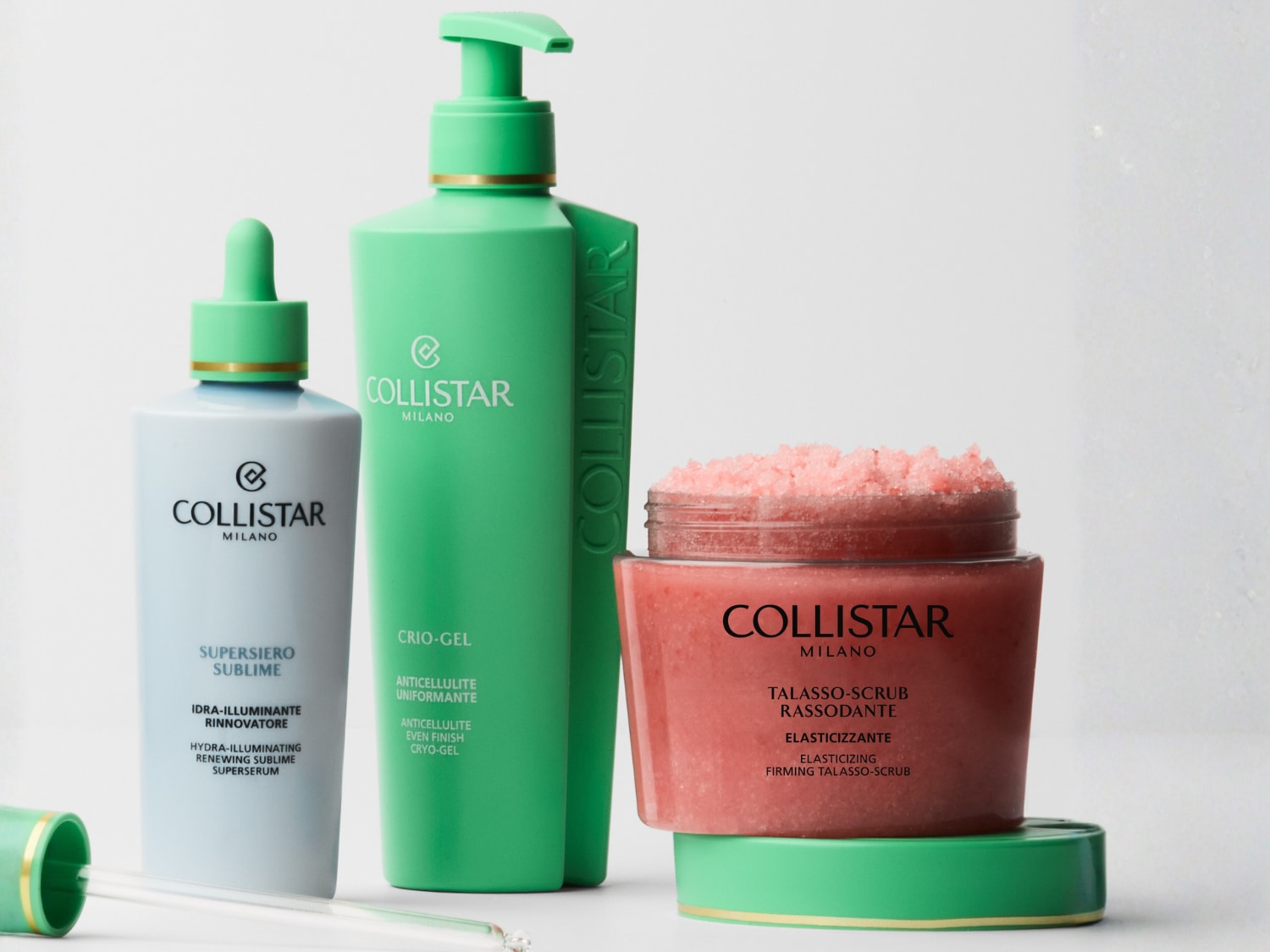 Zestaw kosmetyków Collistar Milano do pielęgnacji ciała: serum w biało-zielonej butelce z pipetą, balsam w zielonej butelce z pompką oraz różowy peeling w słoiczku.