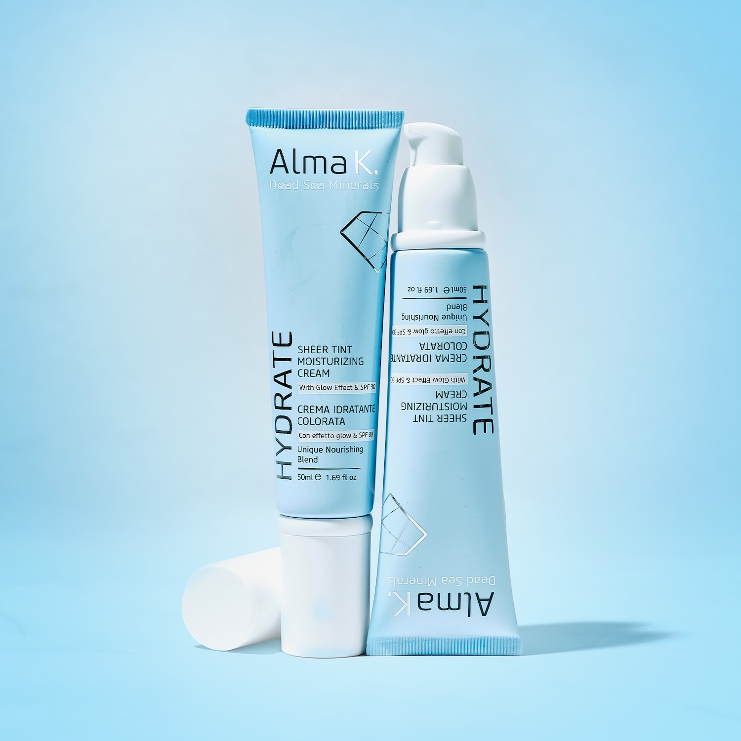 Ecco due confezioni azzurre di crema idratante colorata Alma K. Dead Sea Minerals, per una pelle luminosa e protetta con SPF 30.