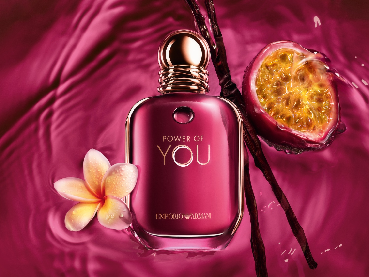 A rózsaszín Armani „Power of You” parfümös üvegcsét virág, maracuja és vaníliarúd díszíti a rózsaszín vízben.