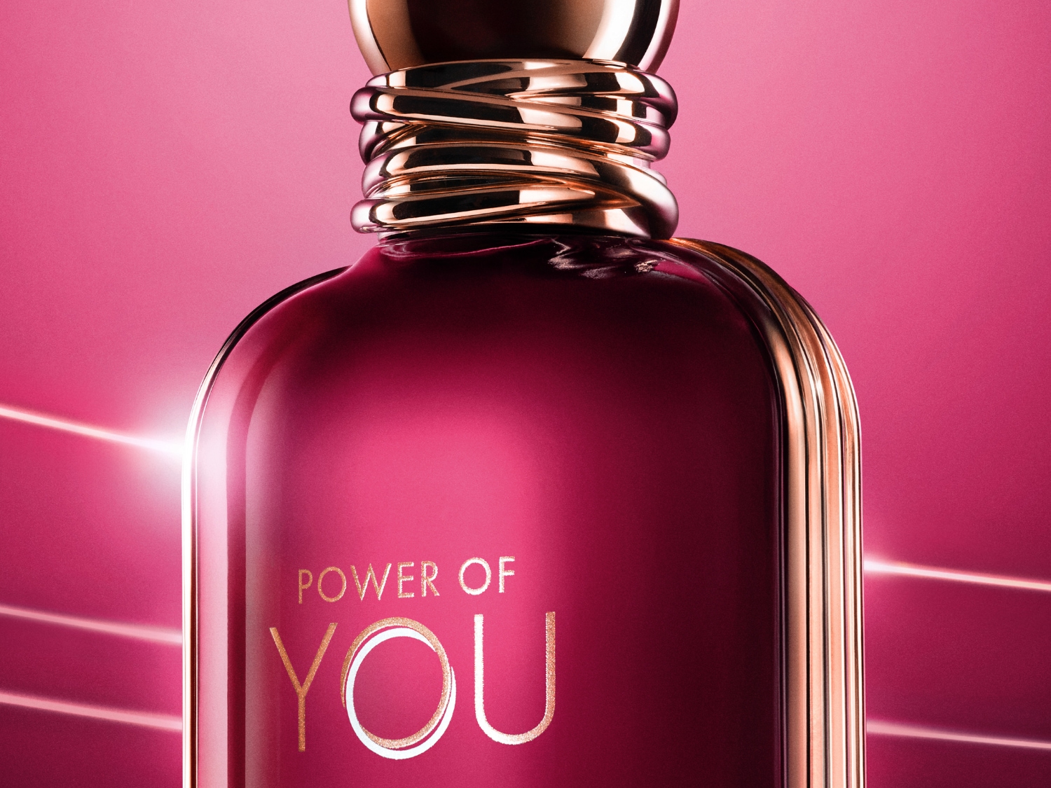 A rózsaszín háttér előtt egy bordó színű parfümös üveg látható, arany színű kupakkal és a "POWER OF YOU" felirattal.