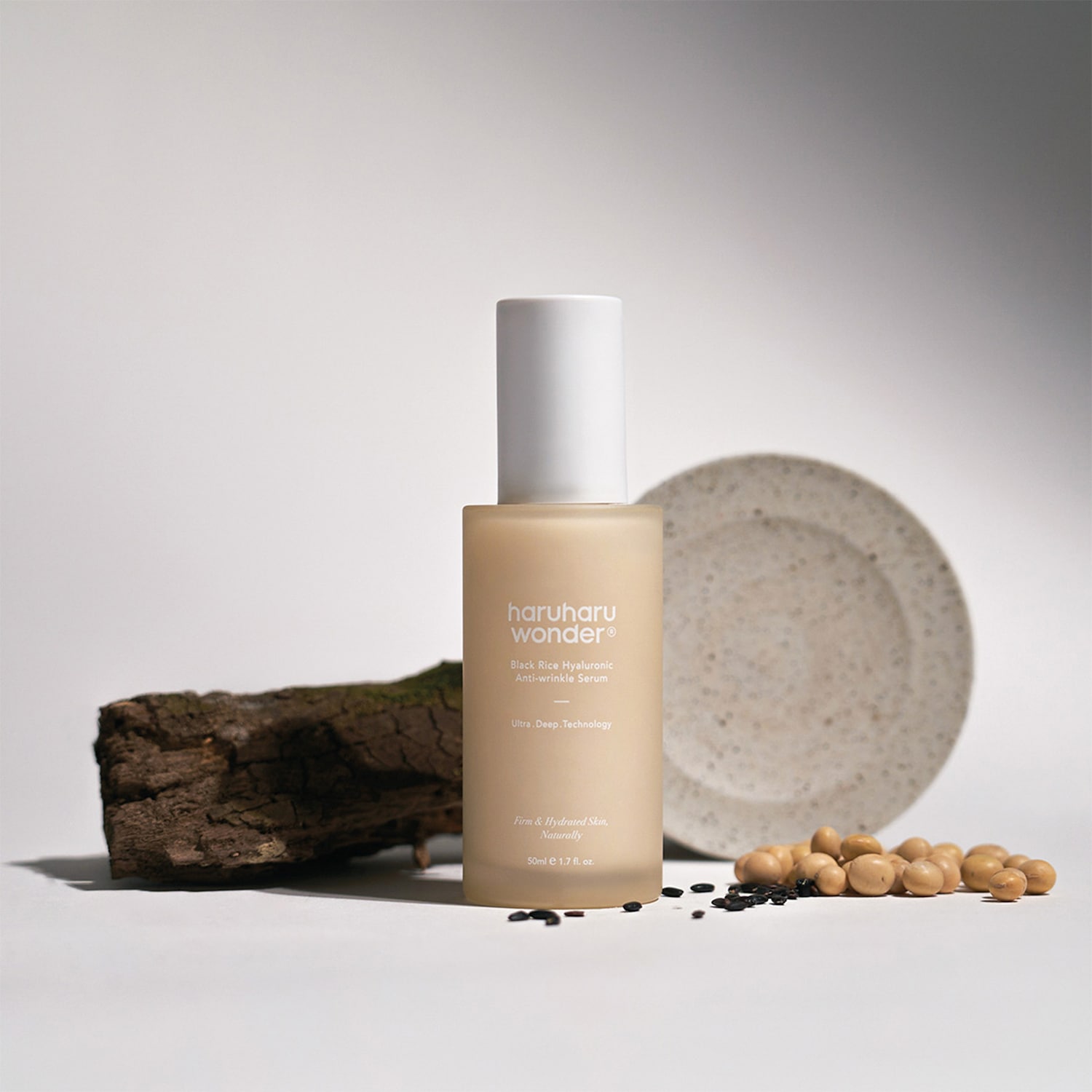 Siero anti-rughe Haruharu Wonder Black Rice Hyaluronic in una bottiglia color crema con tappo bianco, accentuato da elementi naturali come un pezzo di legno, semi di soia e riso nero.