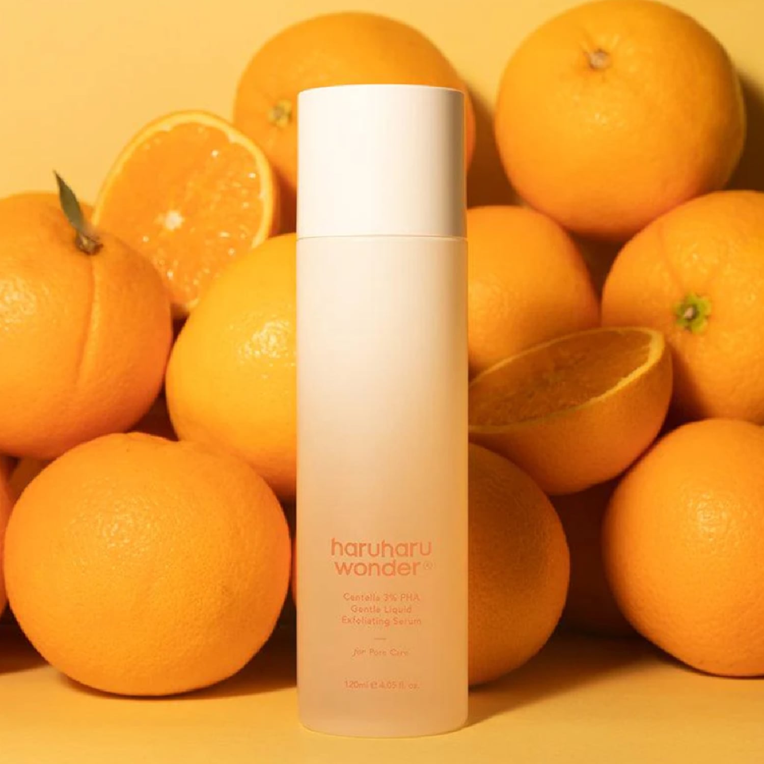 Ecco il siero esfoliante liquido delicato Haruharu Wonder Centella 3% PHA, presentato in un flacone bianco opaco circondato da arance fresche.