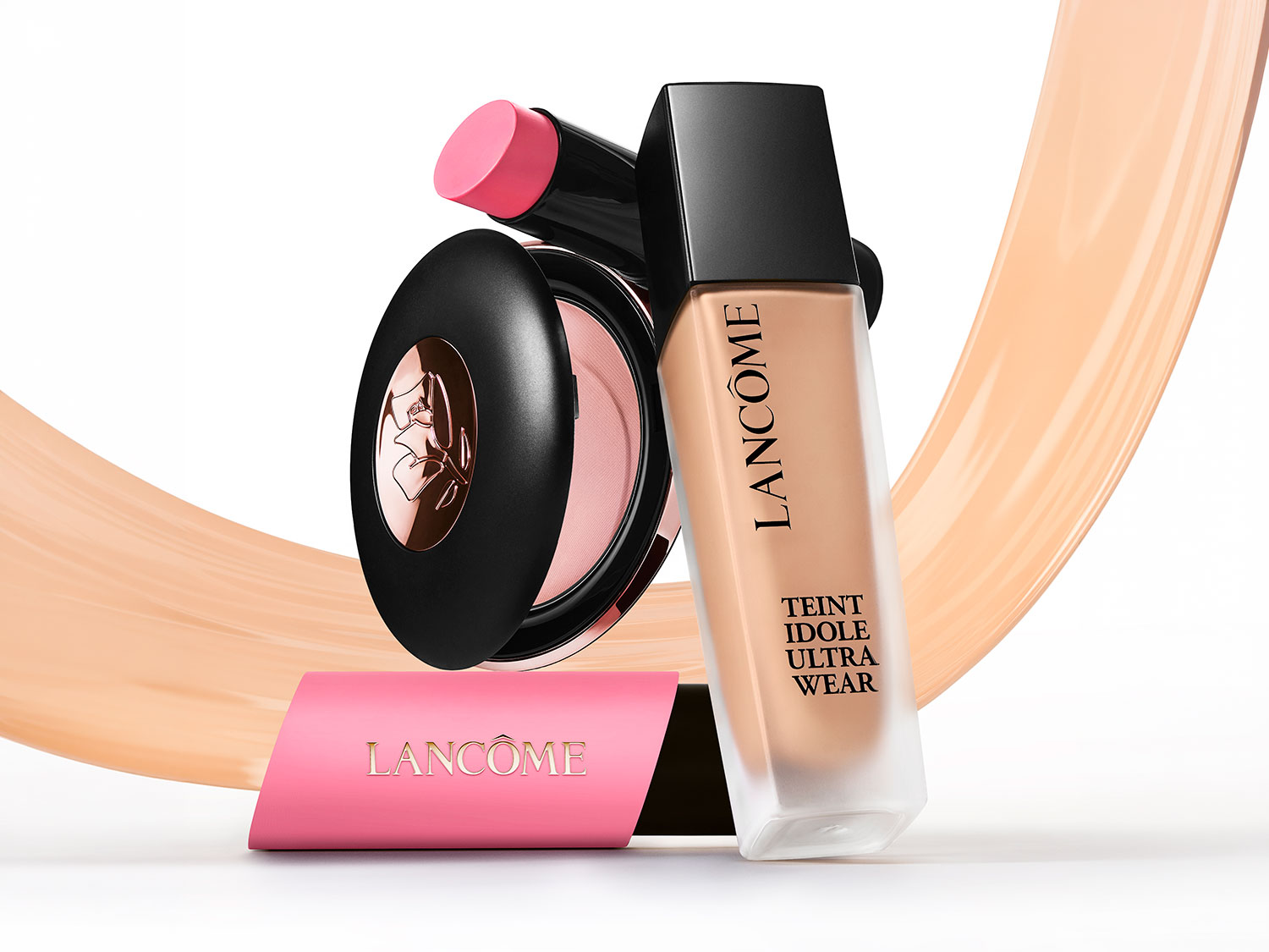 Descoperă trio-ul Lancôme pentru un look impecabil: fond de ten Teint Idole Ultra Wear, blush compact cu logo floral auriu și stick blush roz, toate pe un fundal bej.