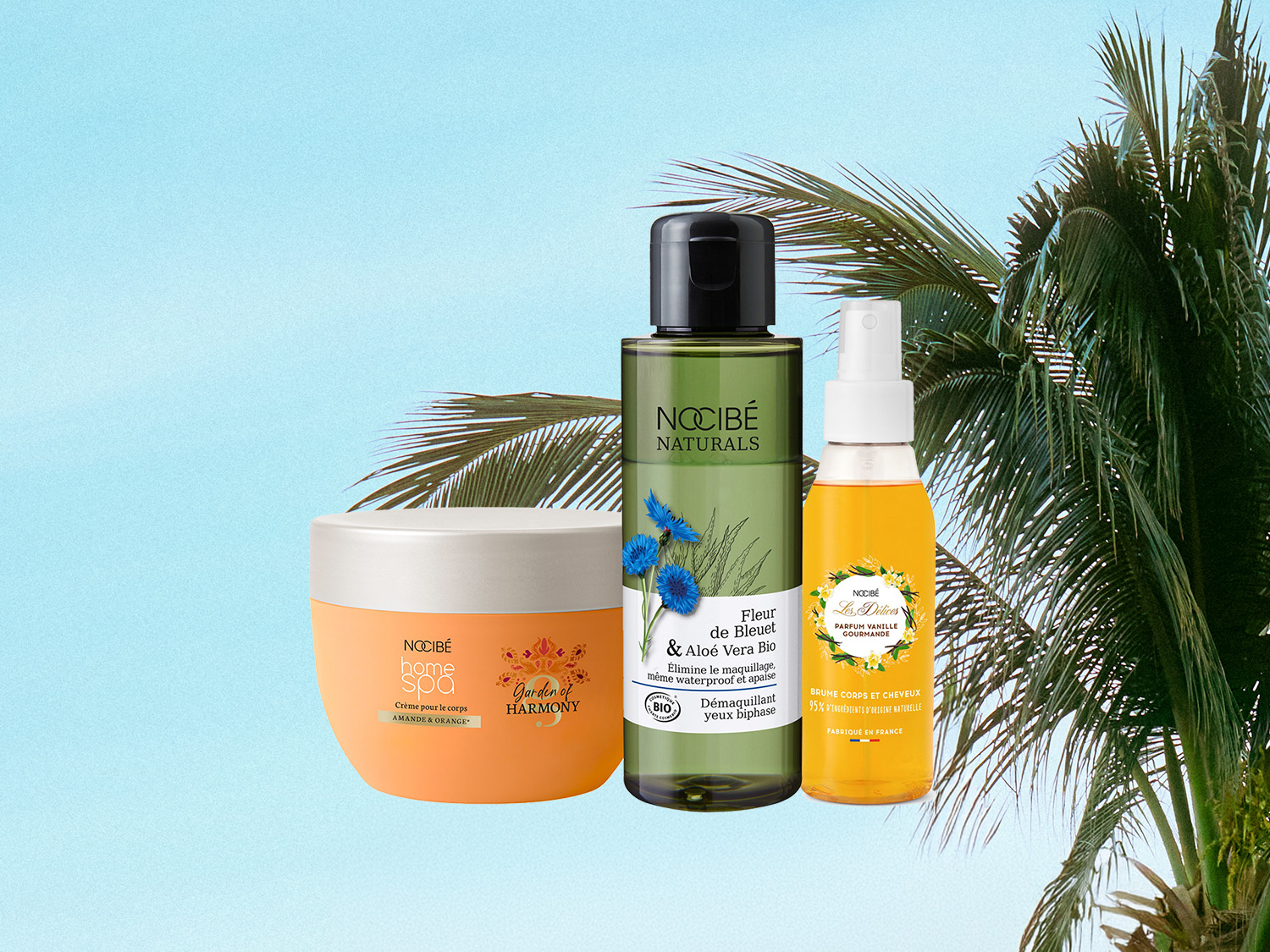 Découvrez la crème pour le corps Nocibé Home Spa Amande & Orange, le démaquillant yeux biphasé Nocibé Naturals Fleur de Bleuet & Aloe Vera Bio, et la brume corps et cheveux Nocibé Les Délices Parfum Vanille Gourmande, présentés sur un fond de ciel bleu avec des palmiers.