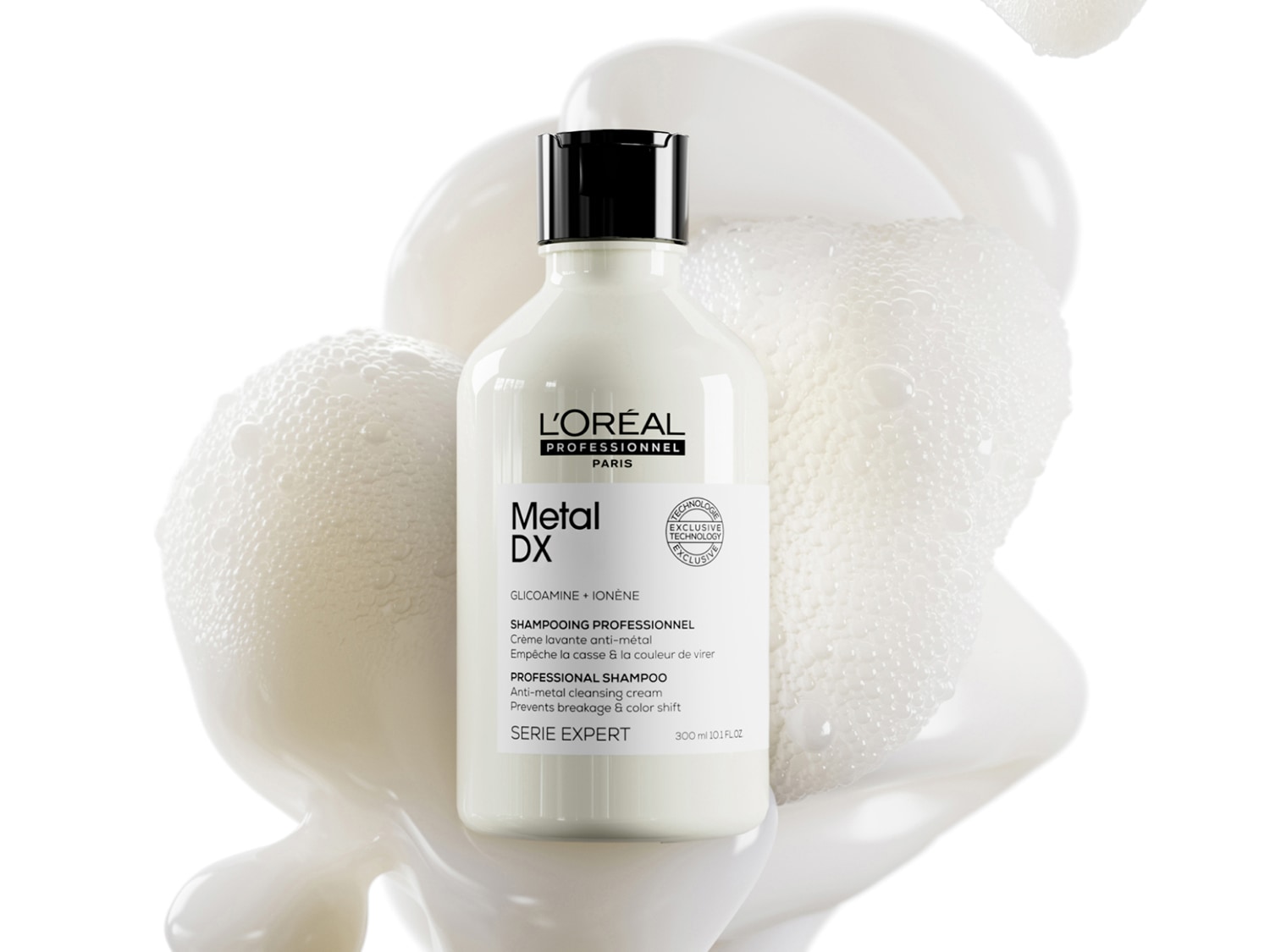 Eine weiße Flasche L'Oréal Professionnel Metal DX Serie Expert Shampoo, eingebettet in eine cremige weiße Textur mit feinen Schaumblasen auf weißem Hintergrund.