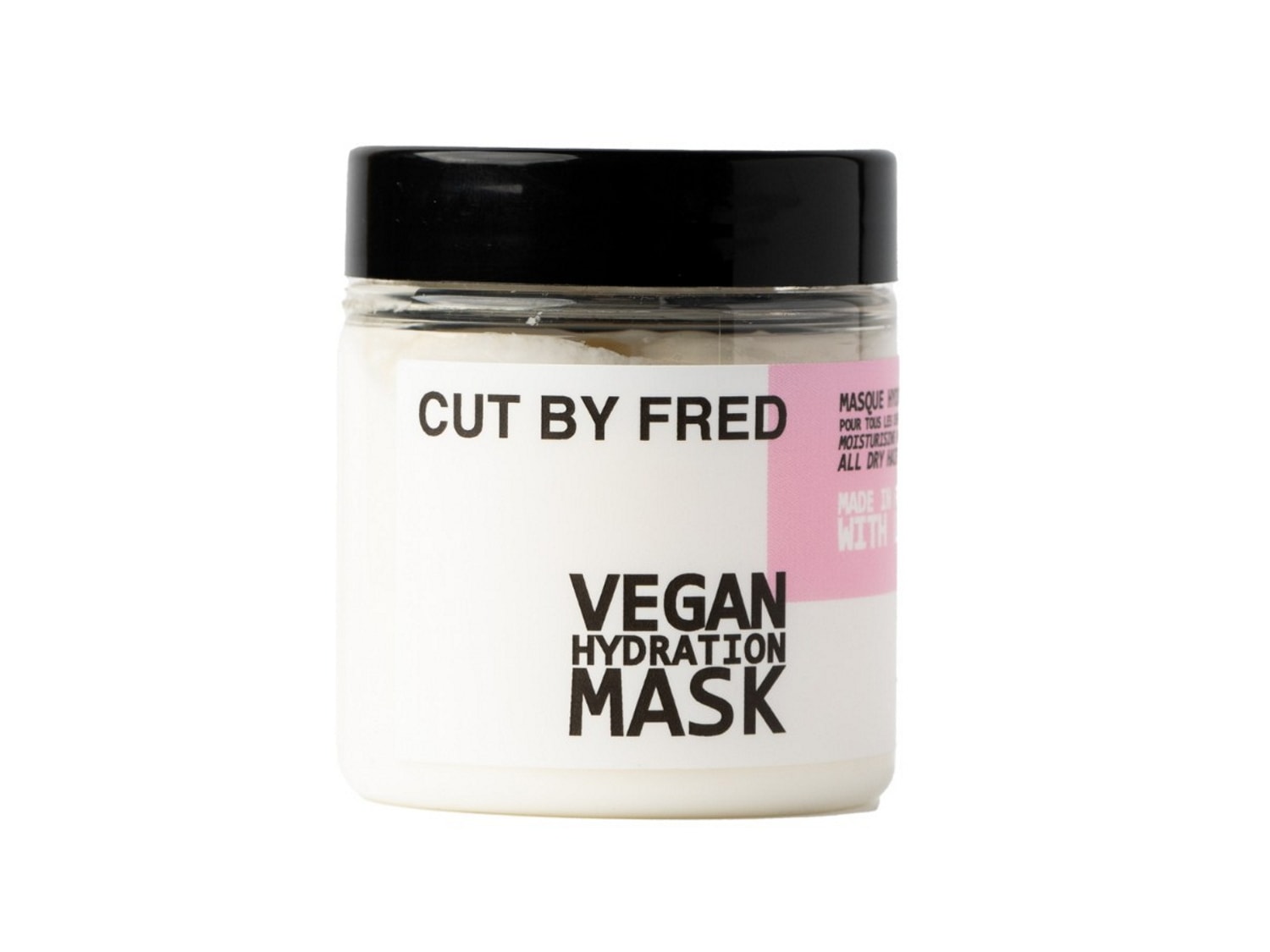 Le masque hydratation vegan Cut By Fred est présenté dans un pot transparent avec un couvercle noir, l'étiquette blanche indique "VEGAN HYDRATION MASK" en noir, avec une bande rose sur le côté droit.