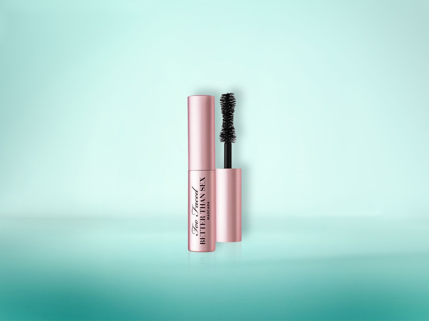Die Too Faced Better Than Sex Mascara in einem rosafarbenen Behälter mit schwarzer Bürste, die für voluminöse Wimpern sorgt, ist auf einem hellblauen Hintergrund abgebildet.