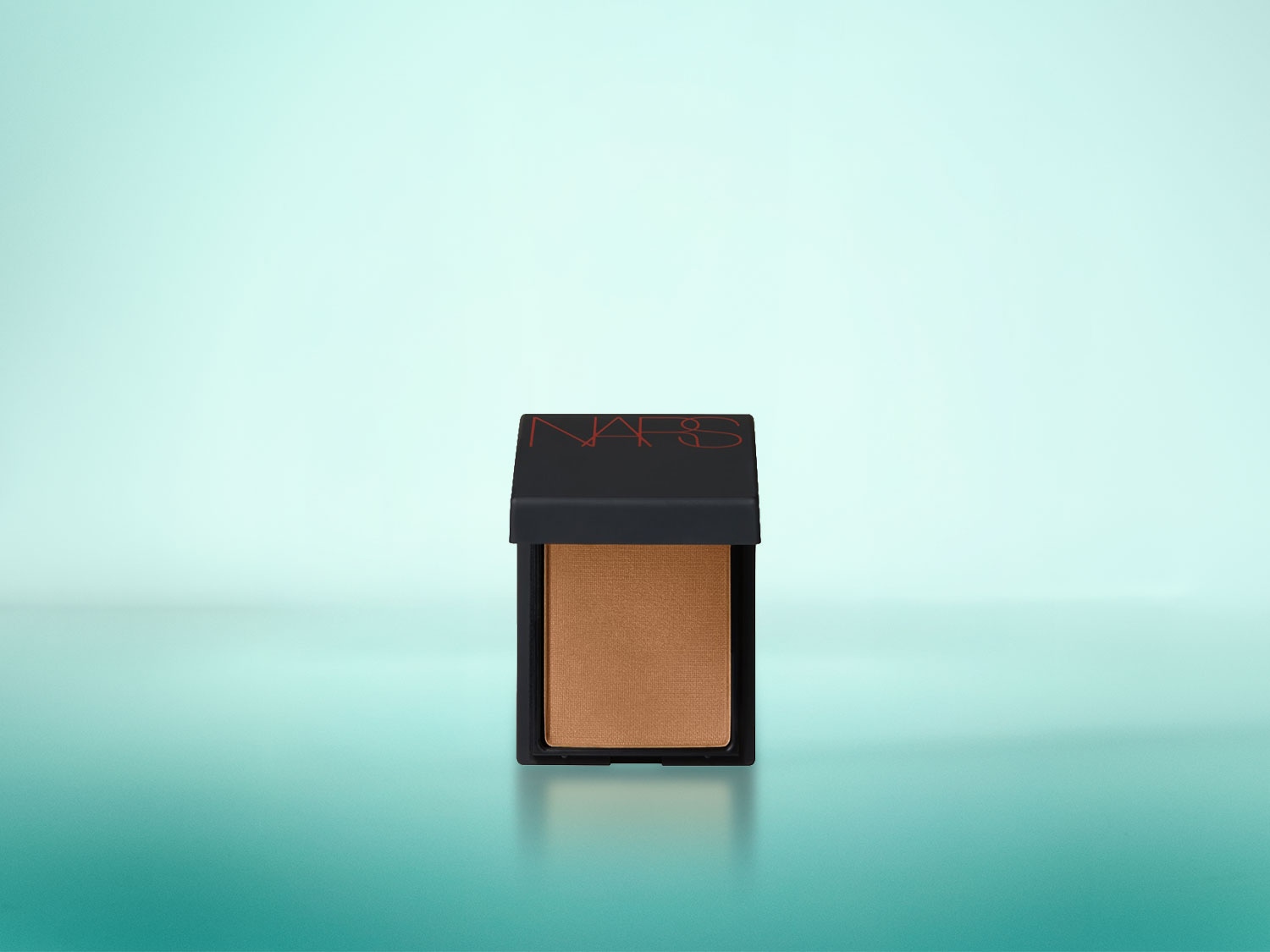Das NARS Bronzing Powder in der Farbe Laguna ist ein mattes, bräunliches Puder in einer schwarzen quadratischen Dose mit rotem NARS-Logo auf dem Deckel, das auf einem hellblauen bis türkisfarbenen Hintergrund steht.