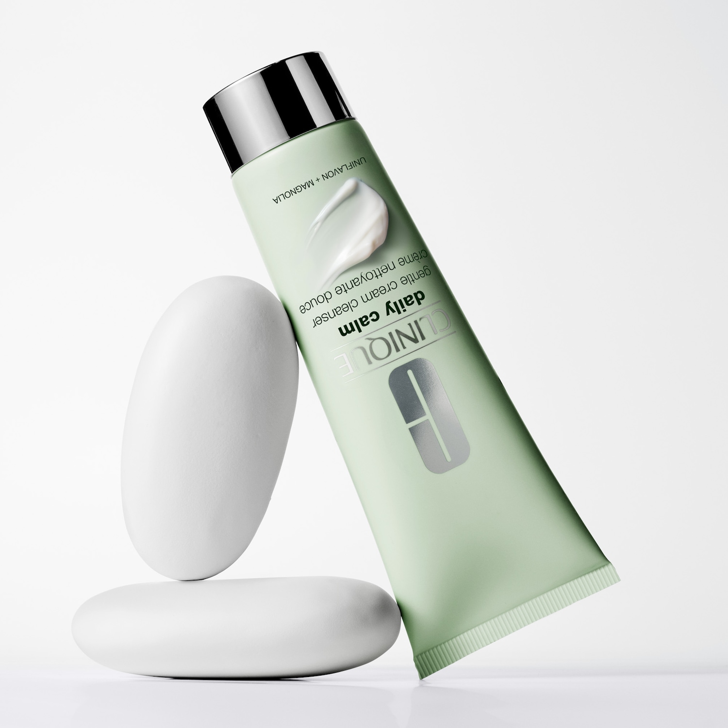 Eine Tube Clinique Daily Calm Cleanser steht auf dem Kopf, angelehnt an zwei gestapelte weiße Steine.