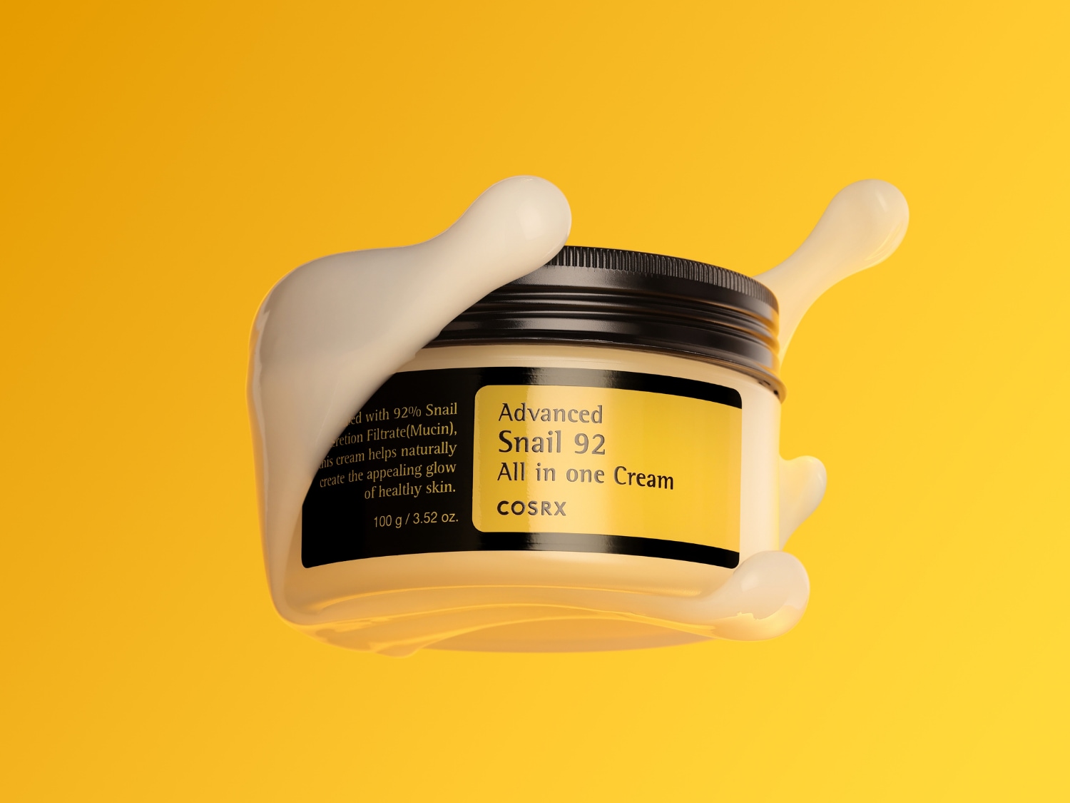 El tarro de crema COSRX Advanced Snail 92 All in one Cream, de color blanco con tapa negra y etiqueta amarilla, está rodeado de una sustancia cremosa que se derrama, destacando su textura rica y su contenido de 92% de filtrado de secreción de caracol para una piel sana y radiante.