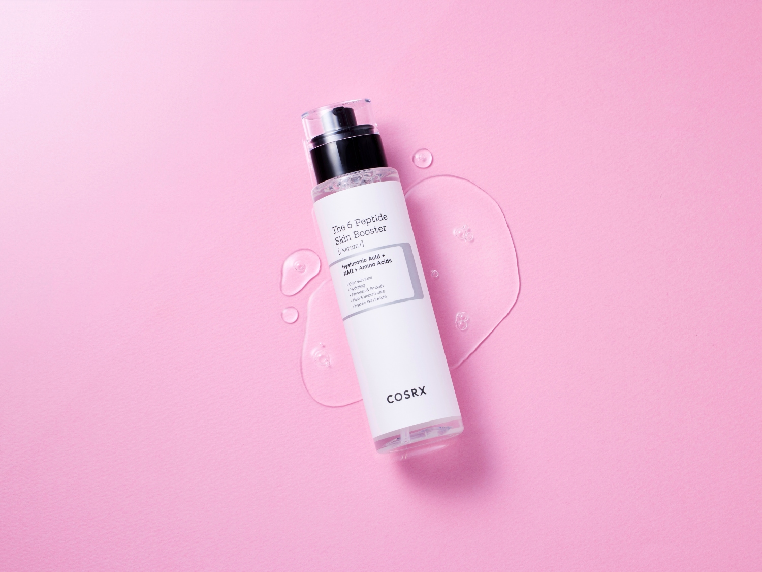 El sérum COSRX The 6 Peptide Skin Booster, en un envase blanco con dispensador negro, se presenta sobre un fondo rosa con gotas de líquido transparente, destacando sus beneficios para una piel uniforme, hidratada y firme.