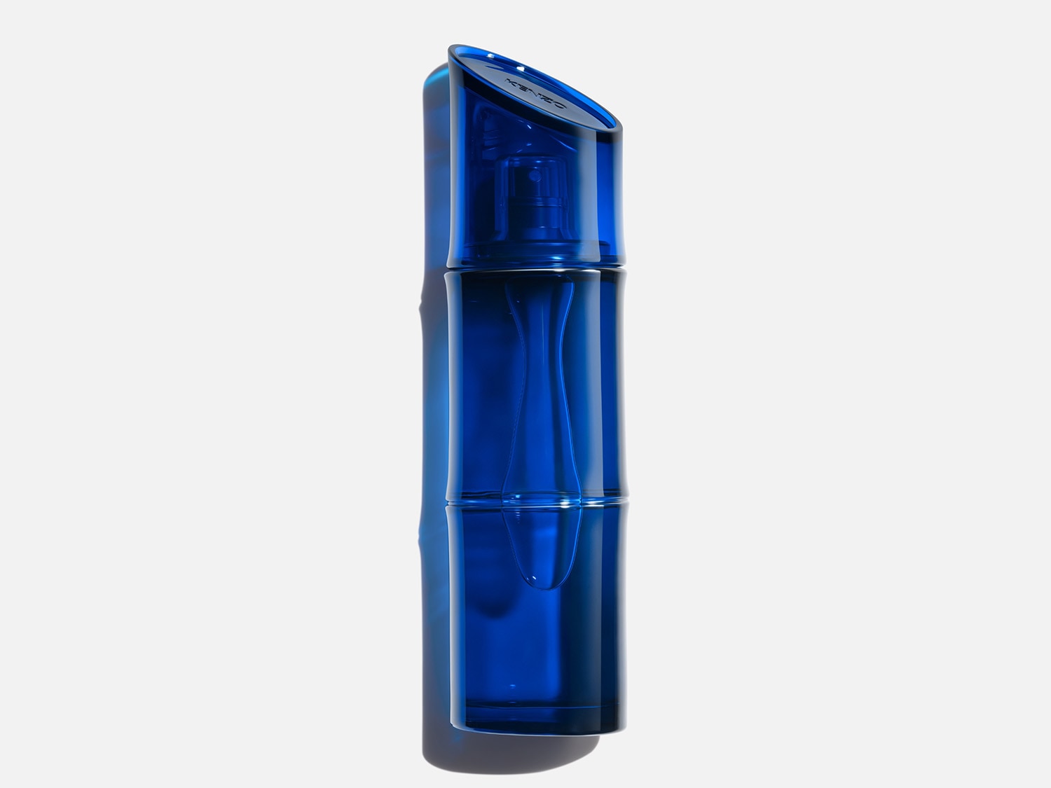 Le parfum Kenzo Homme Eau de Toilette Intense est présenté dans un flacon en verre bleu foncé, avec un bouchon asymétrique et une forme rappelant le bambou, posé sur une surface réfléchissante.