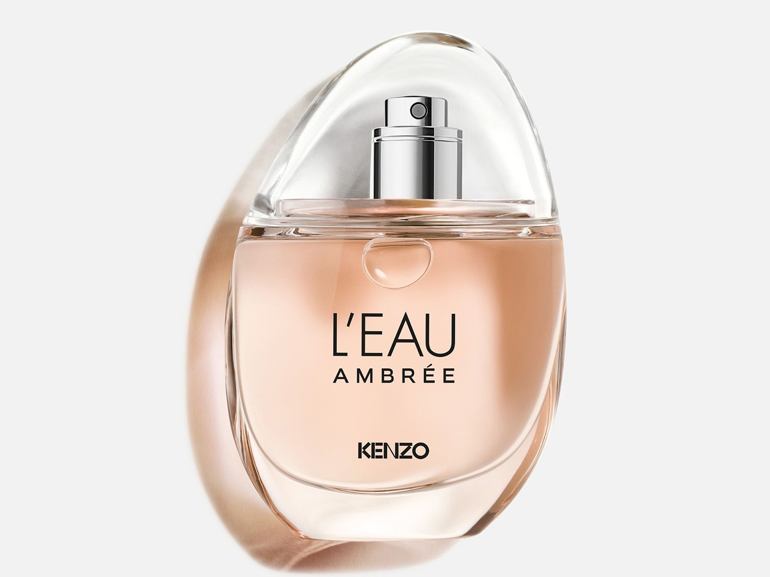 Le parfum L'EAU AMBRÉE de KENZO est présenté dans un flacon en verre transparent avec un liquide ambré, surmonté d'un capuchon transparent et d'un vaporisateur argenté.