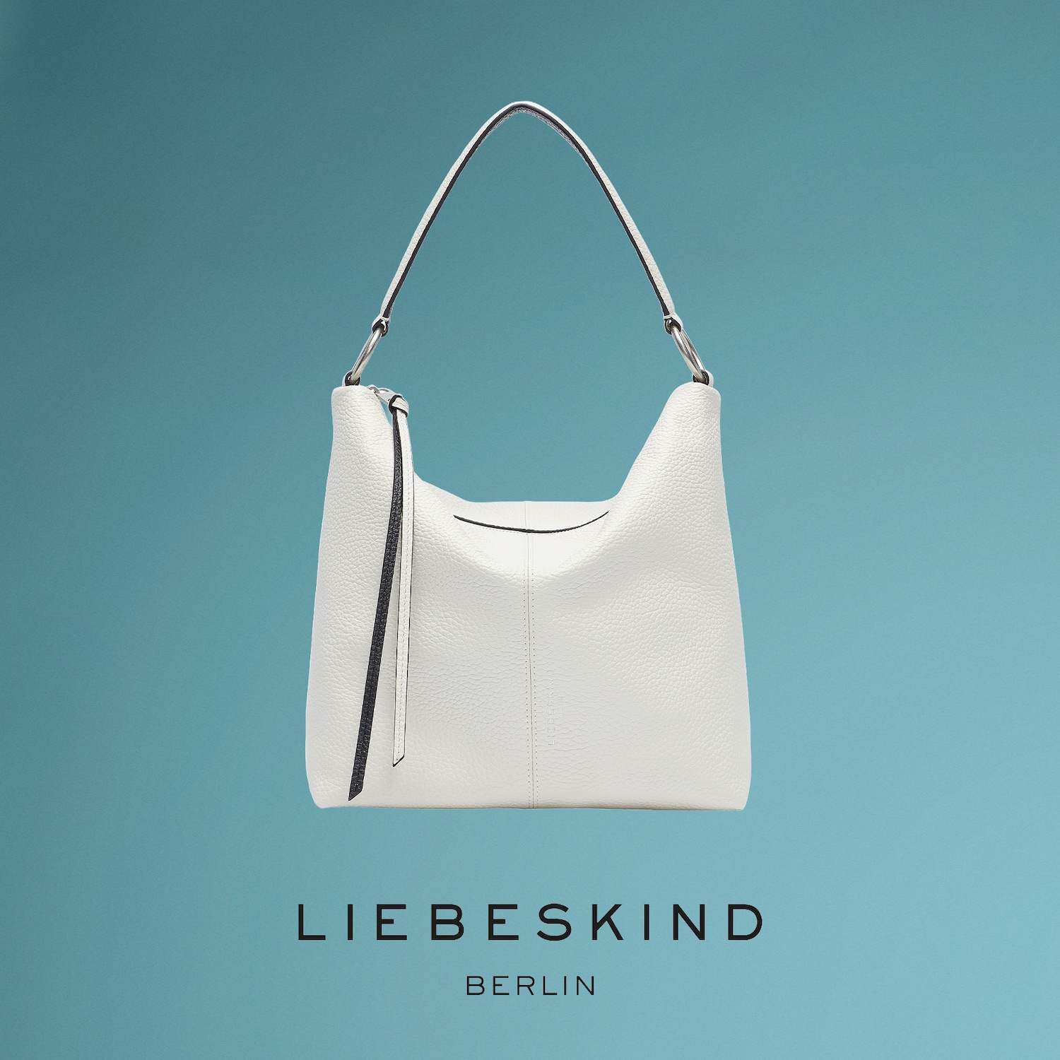 Eine weiße Liebeskind Berlin Handtasche mit genarbter Textur und einem einzelnen Schulterriemen hängt vor einem türkisfarbenen Hintergrund, mit dem Markenlogo in Schwarz darunter.