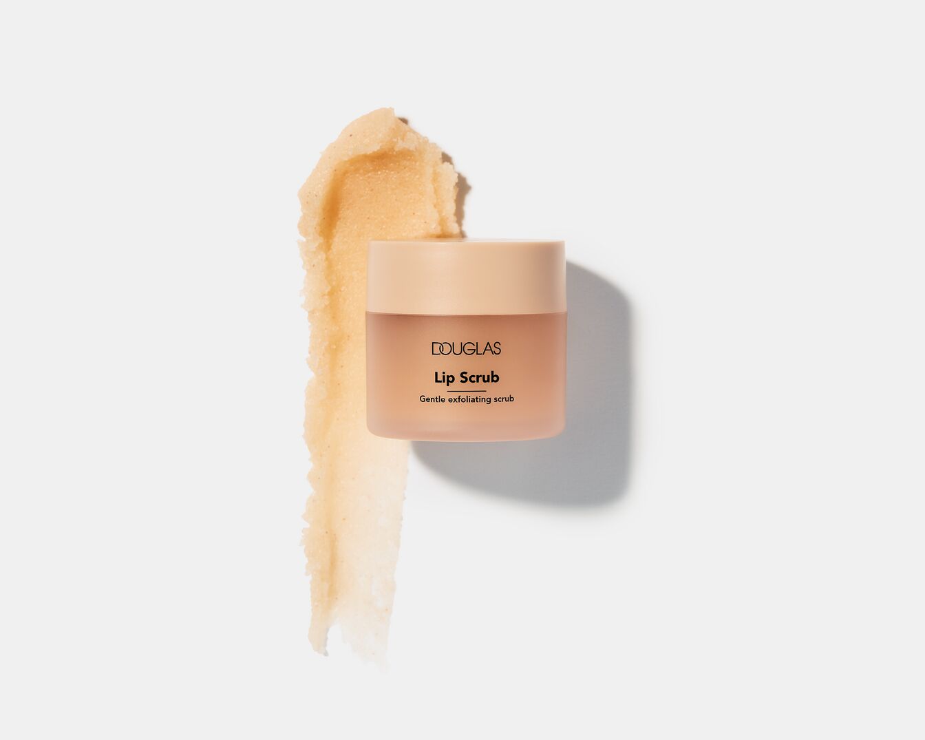De Douglas Lip Scrub is een zachte exfoliërende scrub in een perzikkleurige pot met een beige deksel, perfect voor gladde en zachte lippen.