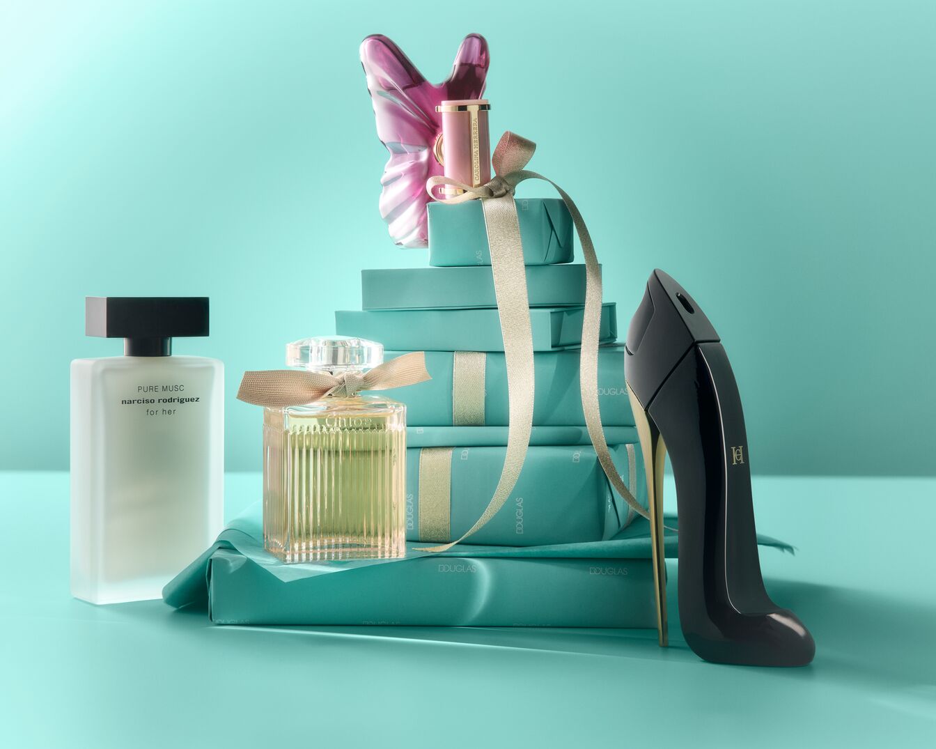 Découvrez une collection de parfums luxueux, incluant Pure Musc de Narciso Rodriguez, présentés avec des cadeaux emballés en bleu sarcelle et un flacon en forme de talon aiguille noir.