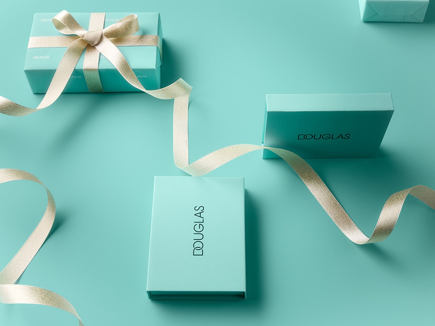 Trois boîtes cadeaux Douglas bleu sarcelle sont présentées sur un fond assorti, avec un ruban doré scintillant qui serpente autour d'elles, ajoutant une touche d'élégance festive.