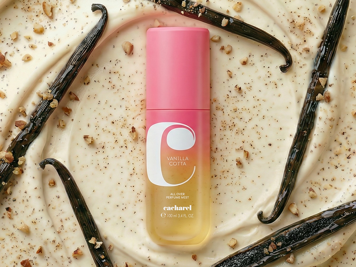 Le parfum Cacharel Vanilla Cotta, un vaporisateur de 100 ml, est présenté sur un fond crémeux parsemé de gousses de vanille et de noix concassées.