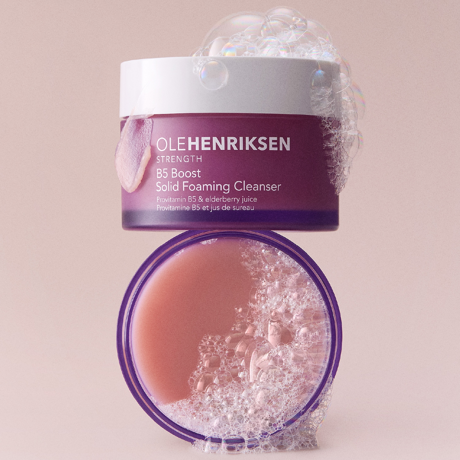 Le nettoyant moussant solide OLEHENRIKSEN B5 Boost, de couleur violette, est enrichi en provitamine B5 et en jus de sureau, avec de la mousse débordant du pot et de son couvercle.