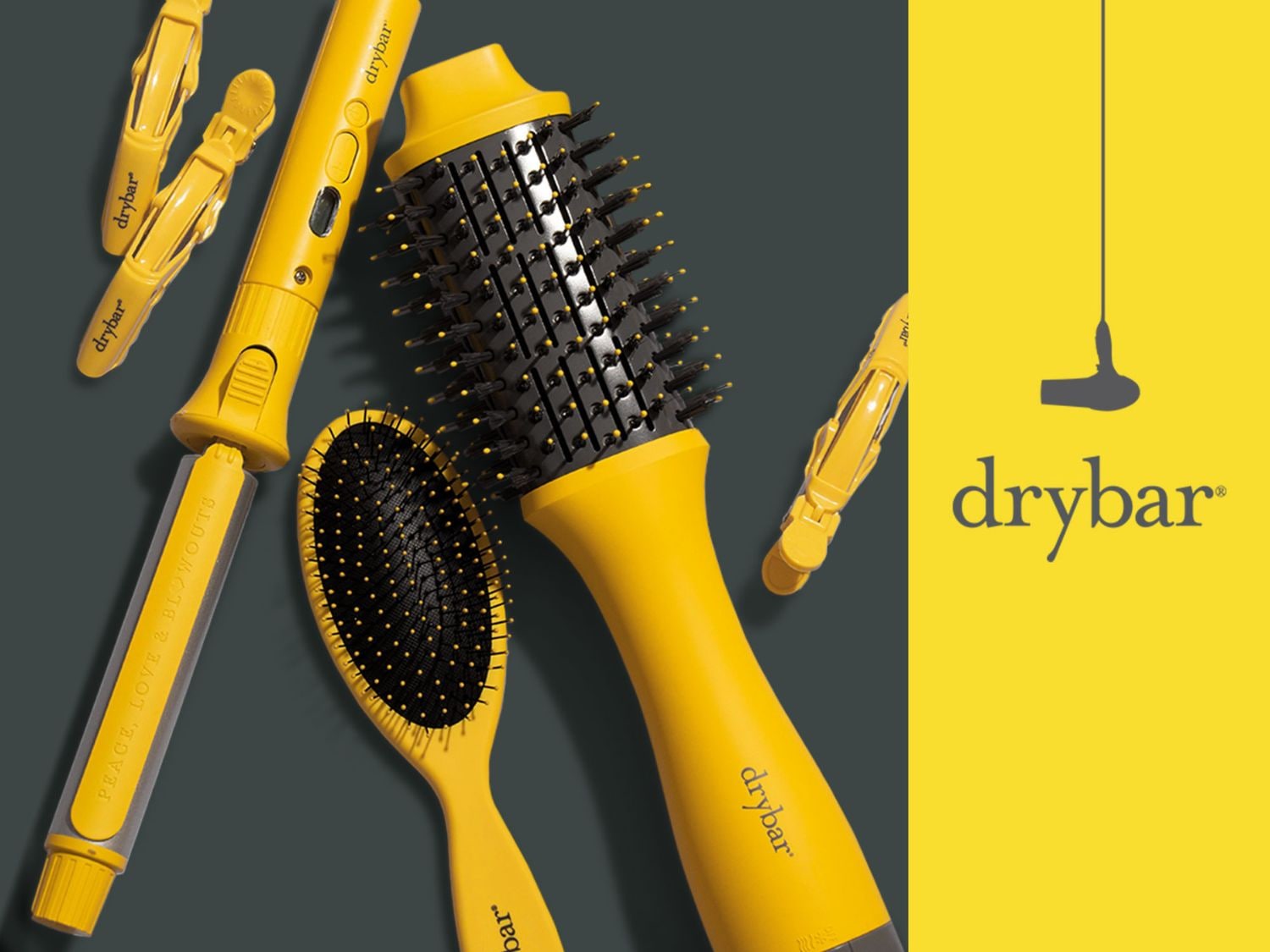 Sada Drybar obsahuje žluté nástroje pro úpravu vlasů, včetně kulmy, kartáče a sponek, které jsou uspořádány na tmavém pozadí s logem Drybar na žlutém pozadí.