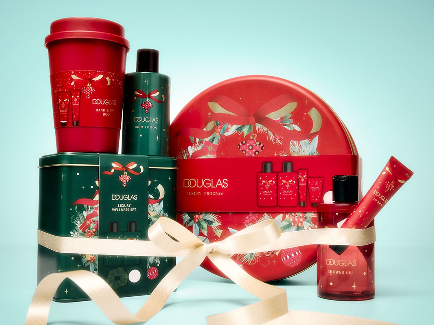 Das Bild zeigt eine festliche Ansammlung von Douglas-Produkten, darunter ein roter Becher mit der Aufschrift "Hand & Lip Duo", eine grüne Flasche "Body Lotion", ein grünes "Luxury Wellness Set" und ein rotes "Luxury Program" mit Duschgel und Lippenbalsam, allesamt mit weihnachtlichen Motiven verziert und mit einem goldenen Band umwickelt.