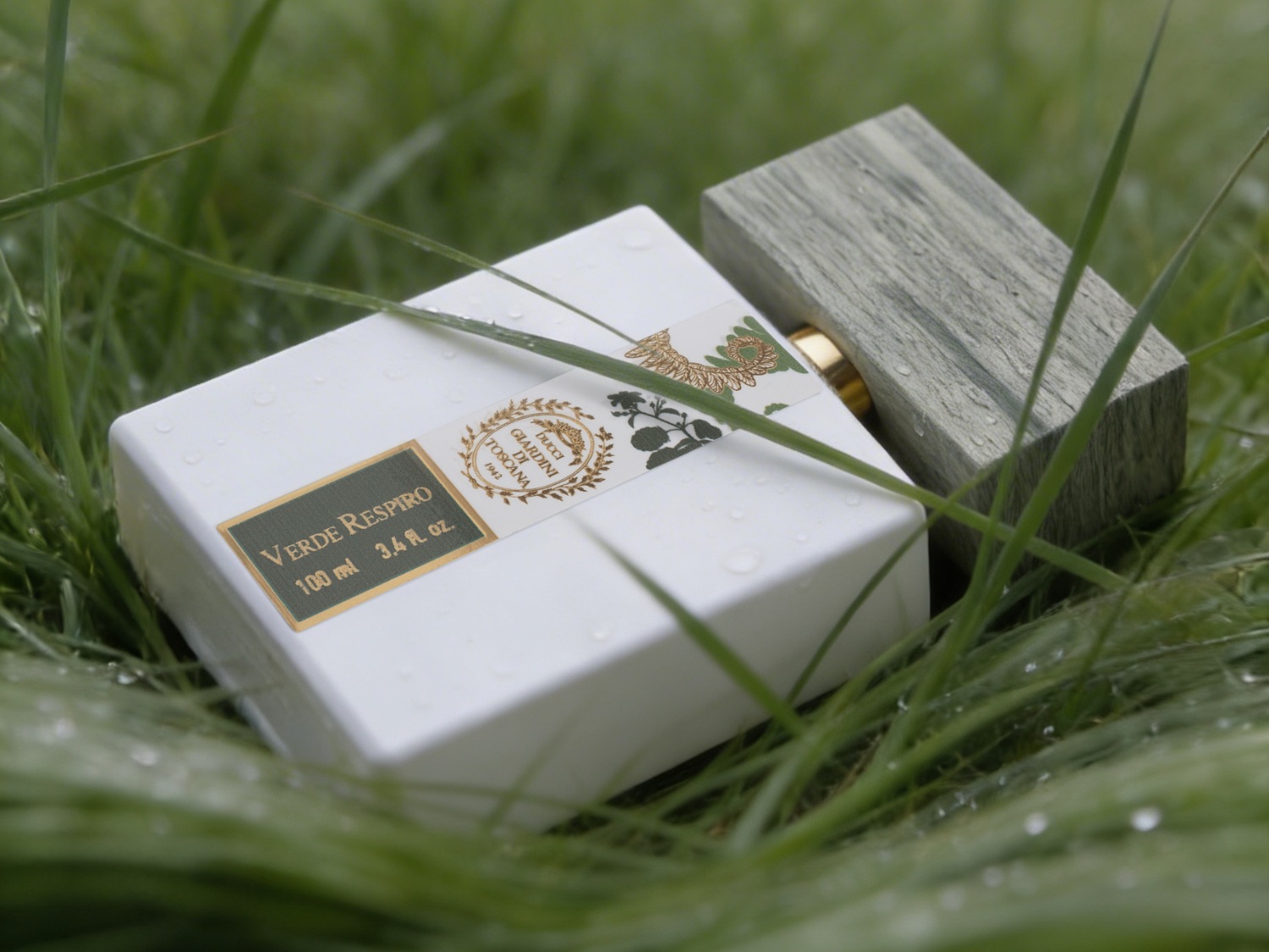 Een witte, rechthoekige parfumfles met een donkergroen etiket met de tekst "VERDE RESPIRO 100 ml 3.4 fl. oz." en een gouden logo, ligt in groen gras met dauwdruppels, naast een rechthoekige houten dop.