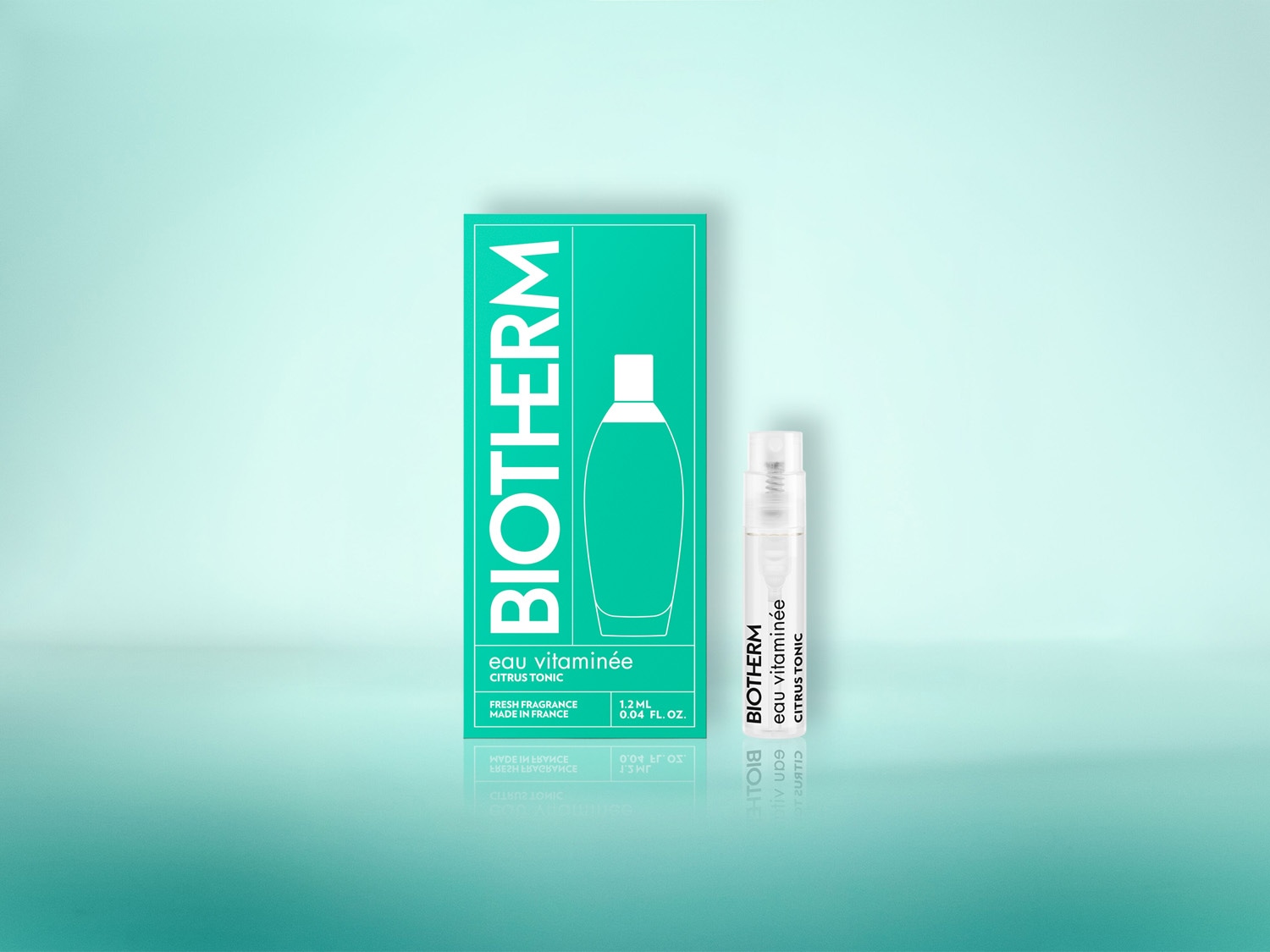 Das Bild zeigt eine grüne Verpackung mit der Aufschrift "BIOTHERM eau vitaminée CITRUS TONIC" und eine kleine, transparente Sprühflasche mit dem gleichen Produkt, die auf einem hellblauen Hintergrund stehen.