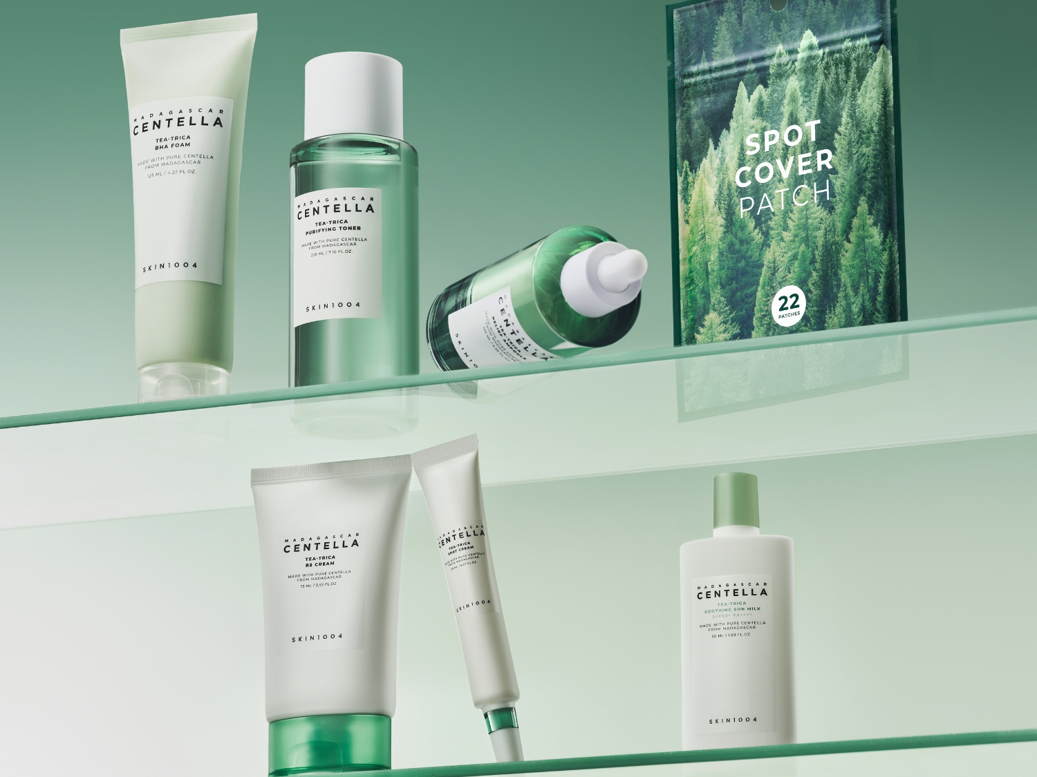 Pianka do mycia twarzy i tonik oczyszczający z serii Madagascar Centella Tea-Trica od Skin1004, w jasnozielonych opakowaniach, stoją na szklanej półce.