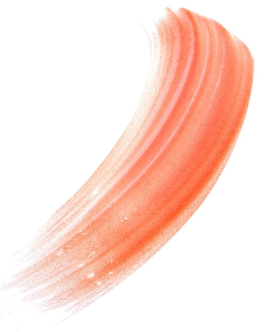 Un échantillon de brillant à lèvres pêche avec des paillettes est étalé en un coup de pinceau incurvé sur un fond blanc.