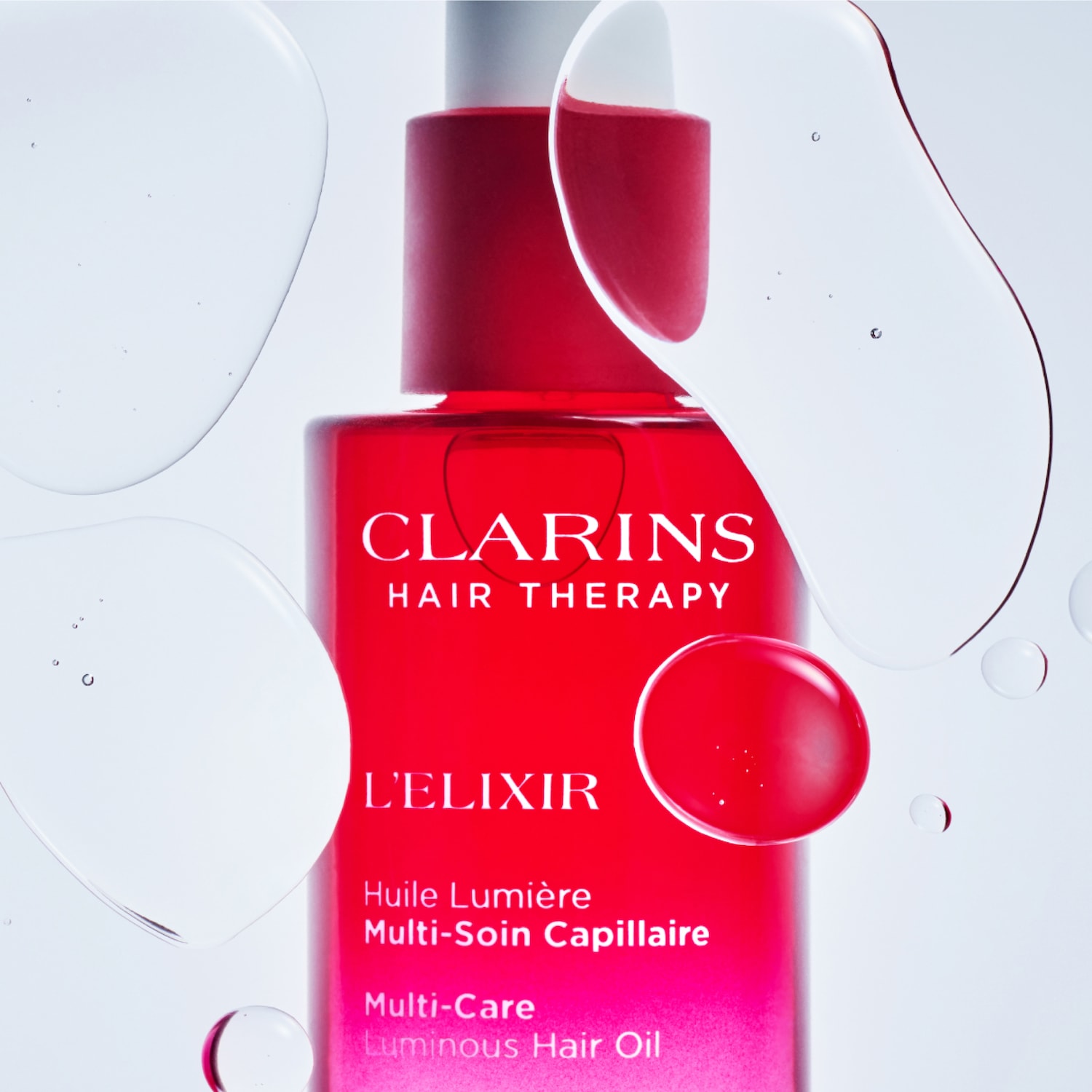 Clarins Hair Therapy L'Elixir Multi-Care Luminous Hair Oil in a vibrant red bottle with a white pump, surrounded by clear, shimmering oil droplets, promises radiant, healthy-looking hair.