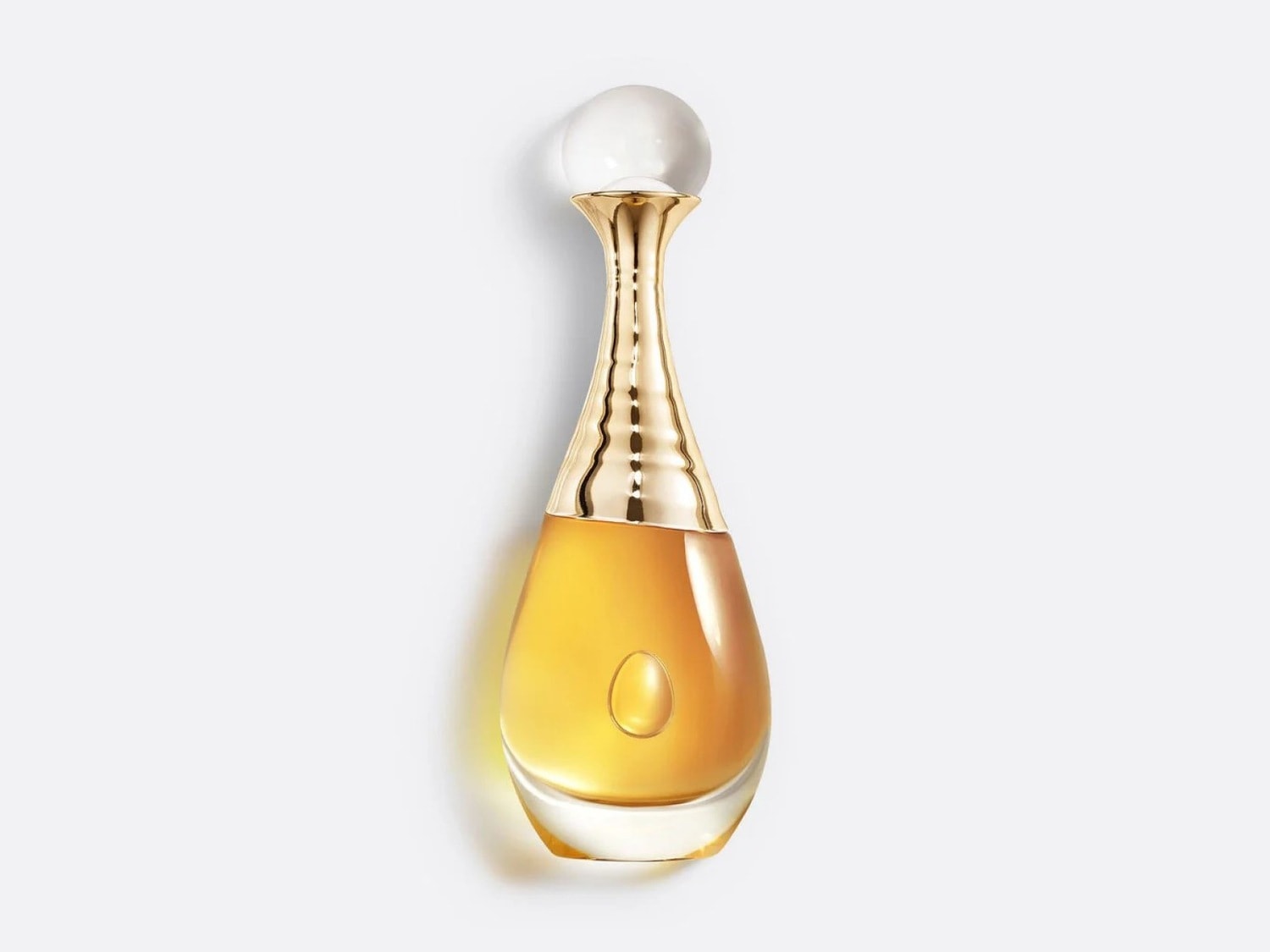 Le parfum J'adore de Dior est présenté dans un flacon en verre transparent en forme de goutte, avec un liquide doré et un bouchon doré orné d'une perle blanche.