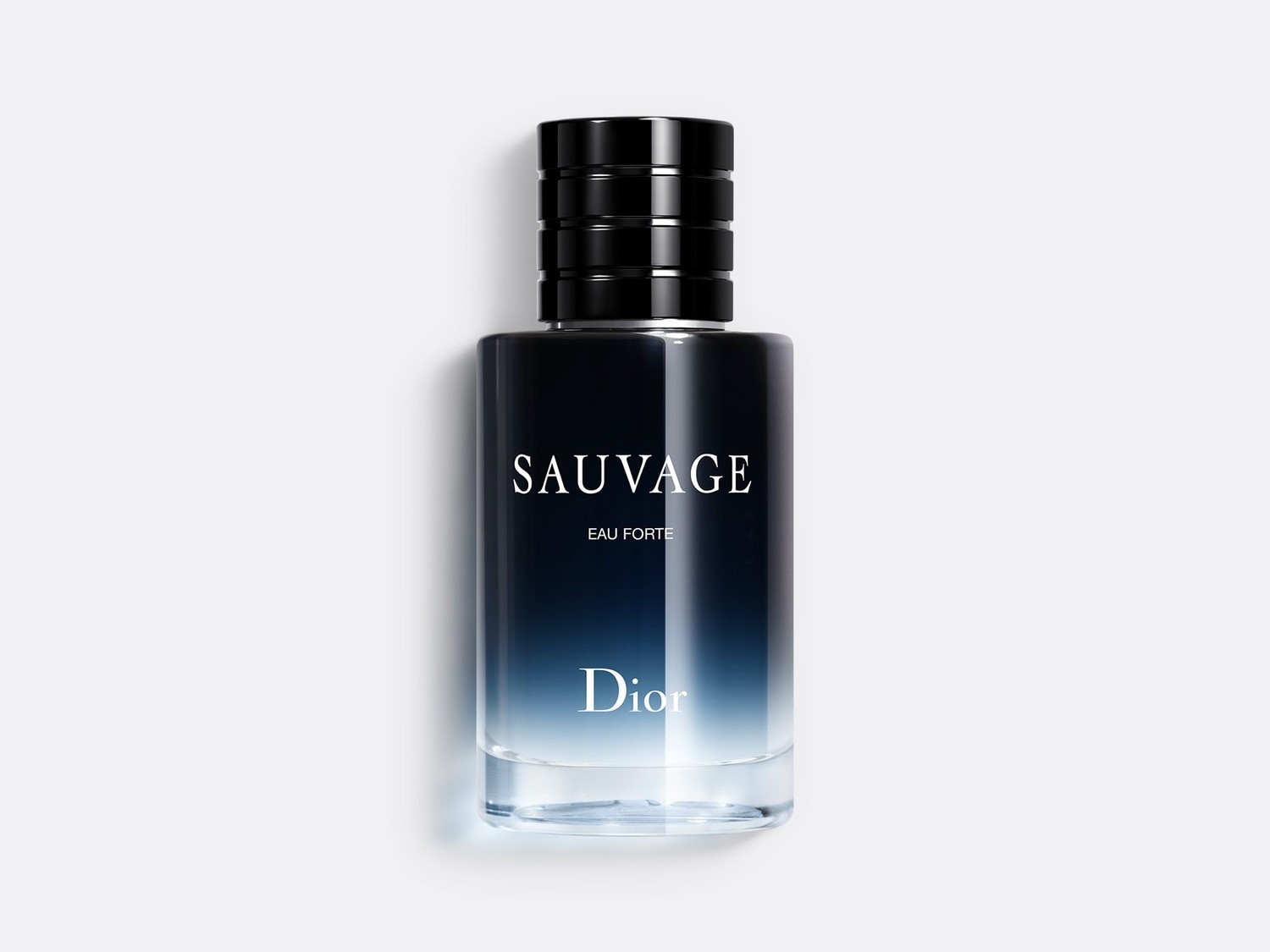 Le parfum Sauvage Eau Forte de Dior est présenté dans un flacon en verre dégradé, passant du noir intense au bleu clair, avec un bouchon noir texturé et les noms "SAUVAGE" et "Dior" en blanc.