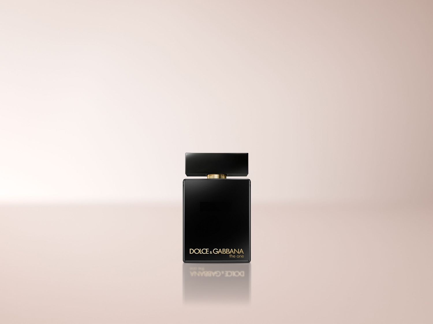 Der Dolce & Gabbana The One For Men Eau de Parfum ist ein eleganter, schwarzer Flakon mit goldenen Akzenten, der auf einem hellrosa Hintergrund steht und sich in der glänzenden Oberfläche spiegelt.