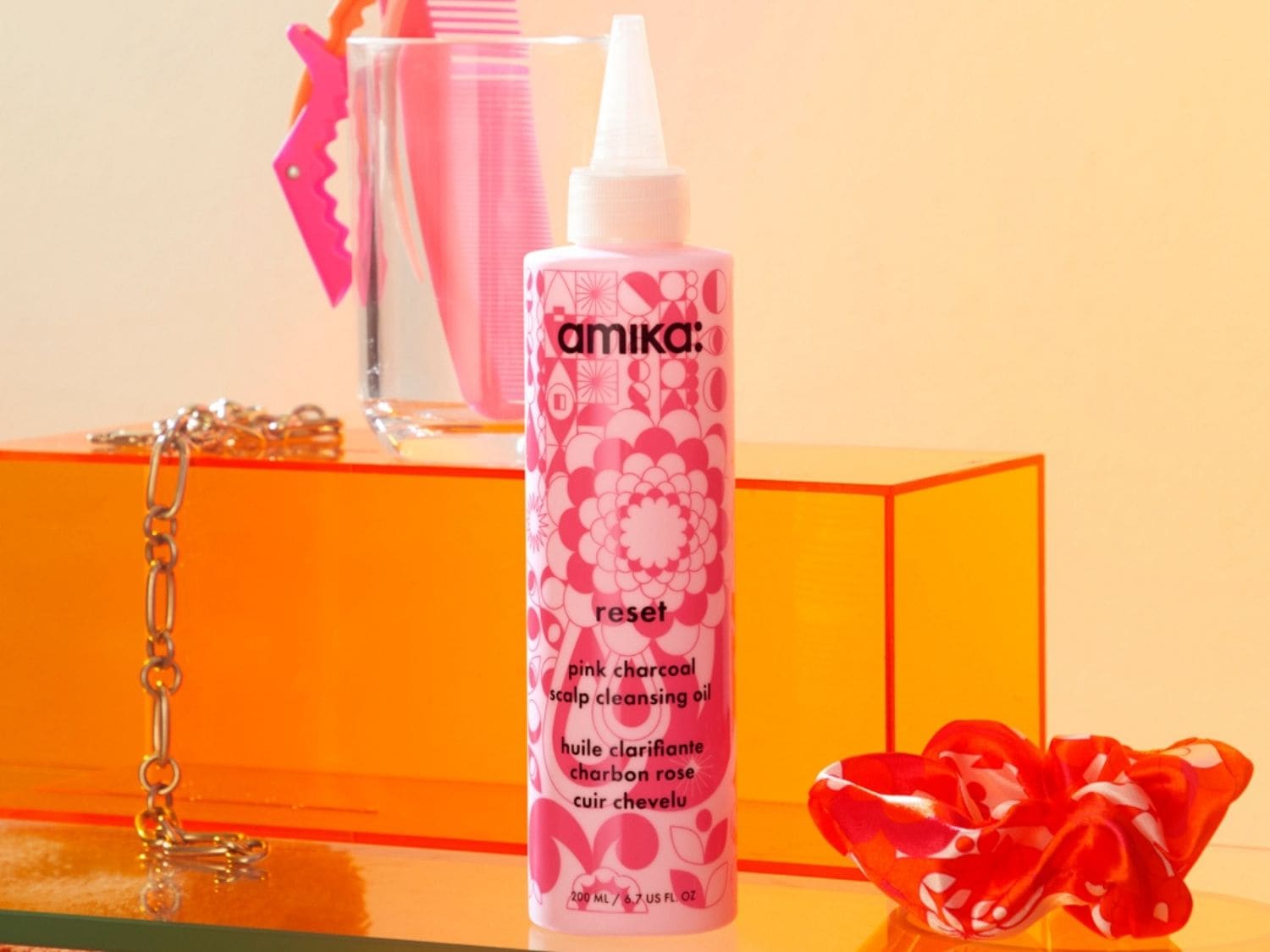 Die Amika Reset Pink Charcoal Scalp Cleansing Oil Flasche ist weiß mit einem rosa Blumenmuster und enthält 200 ml des Produkts, das für die Reinigung der Kopfhaut entwickelt wurde.