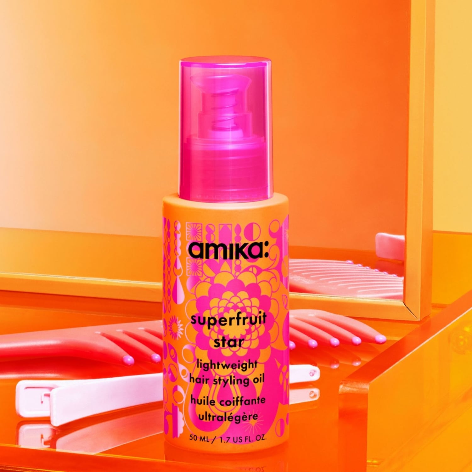 Das Amika Superfruit Star Lightweight Haarstyling-Öl in einer leuchtend orangefarbenen Flasche mit pinkem Pumpverschluss und floralem Muster, perfekt für glänzendes Haar.