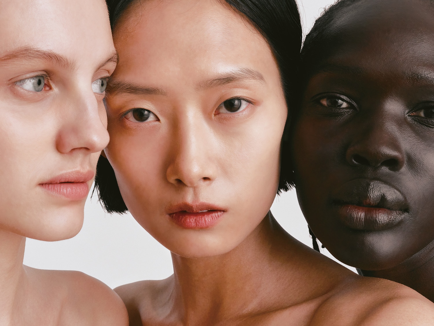 Tre donne con diverse tonalità di pelle, che vanno dal chiaro allo scuro, sono raffigurate in un primo piano che mette in risalto la bellezza e la diversità della pelle.
