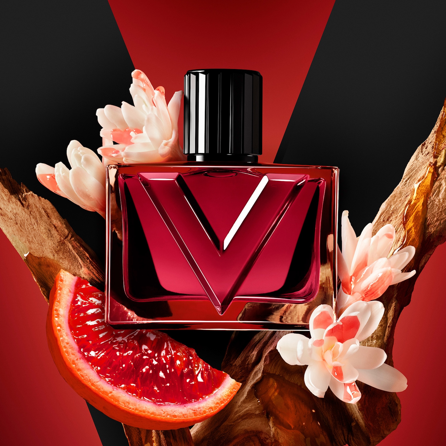 Ein roter Parfümflakon mit einem schwarzen Deckel und einem silbernen V-Logo ist von weißen Blüten, einer Scheibe Blutorange und Holzstücken umgeben, alles auf einem rot-schwarzen Hintergrund.