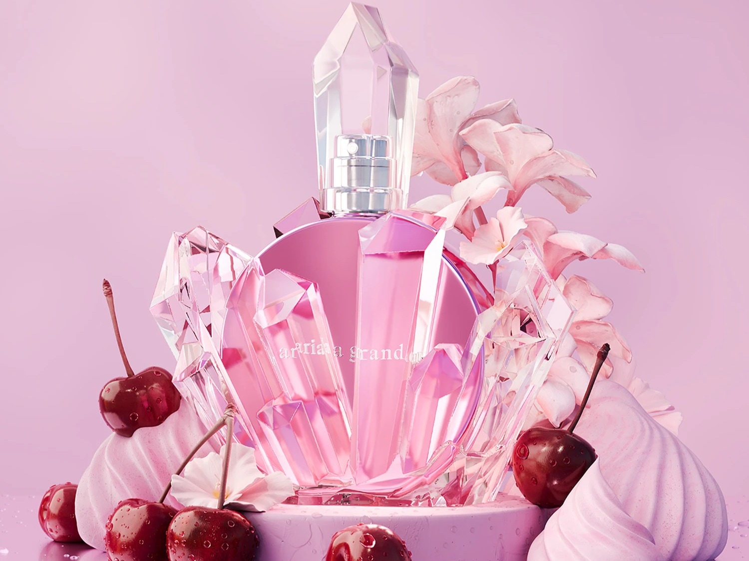 Ariana Grande's pink perfume bottle, adorned with crystal-like shards and delicate pink flowers, is elegantly displayed alongside fresh cherries and pink meringue swirls, all set against a soft pink background.